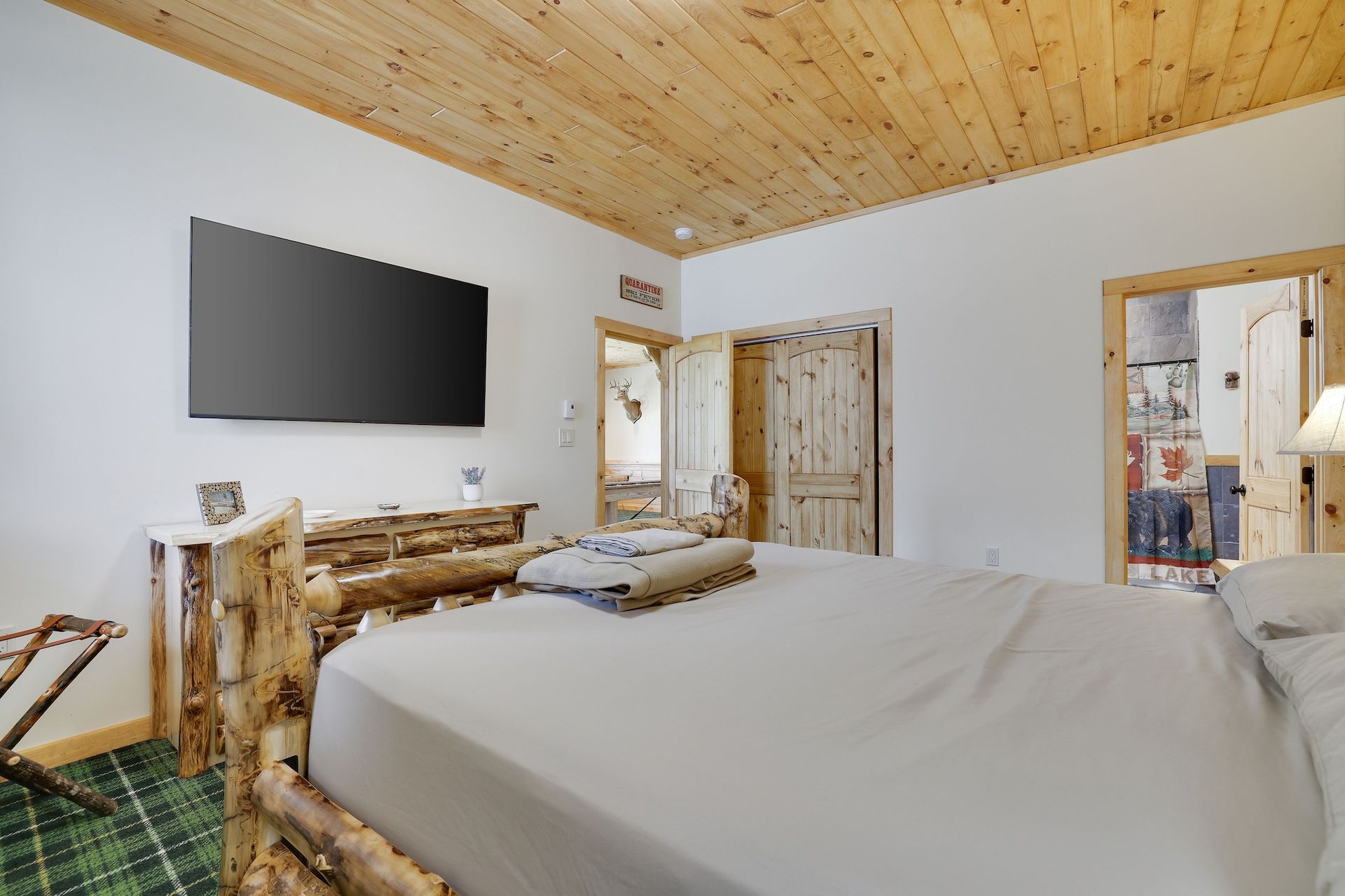 A bedroom with a large bed and a flat screen tv on the wall.