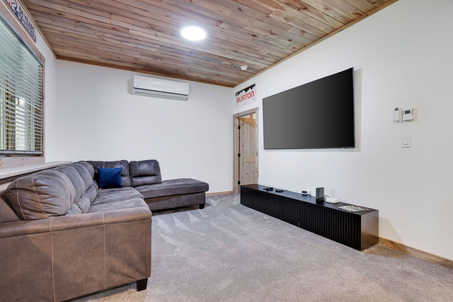 A living room with a couch and a flat screen tv on the wall.