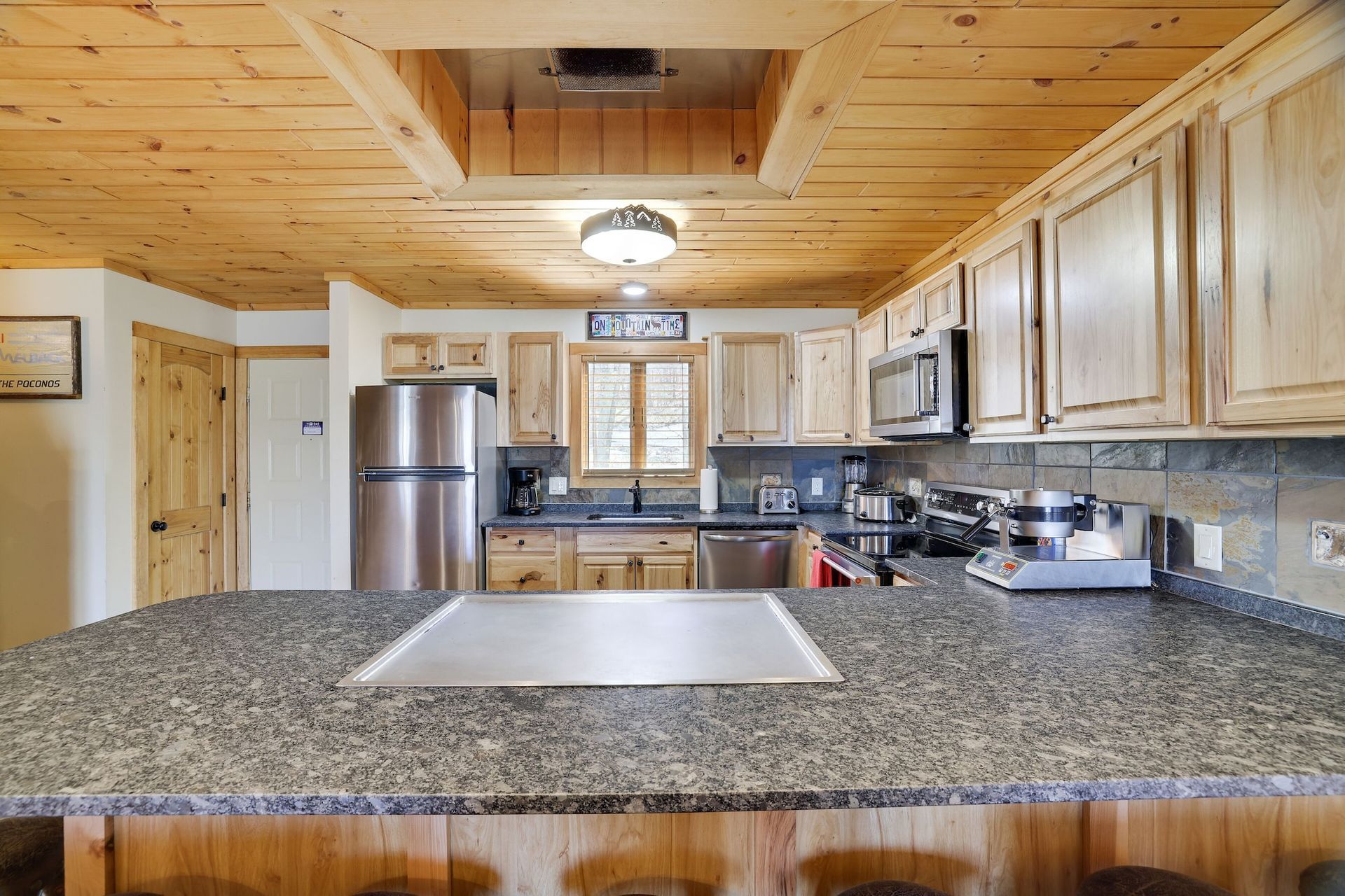 A kitchen with granite counter tops , stainless steel appliances , and wooden cabinets.