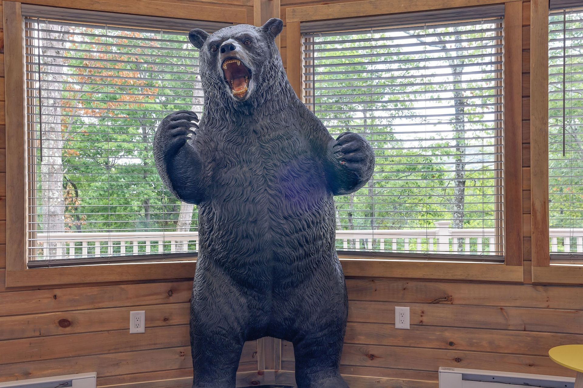 A statue of a bear is standing in front of a window.
