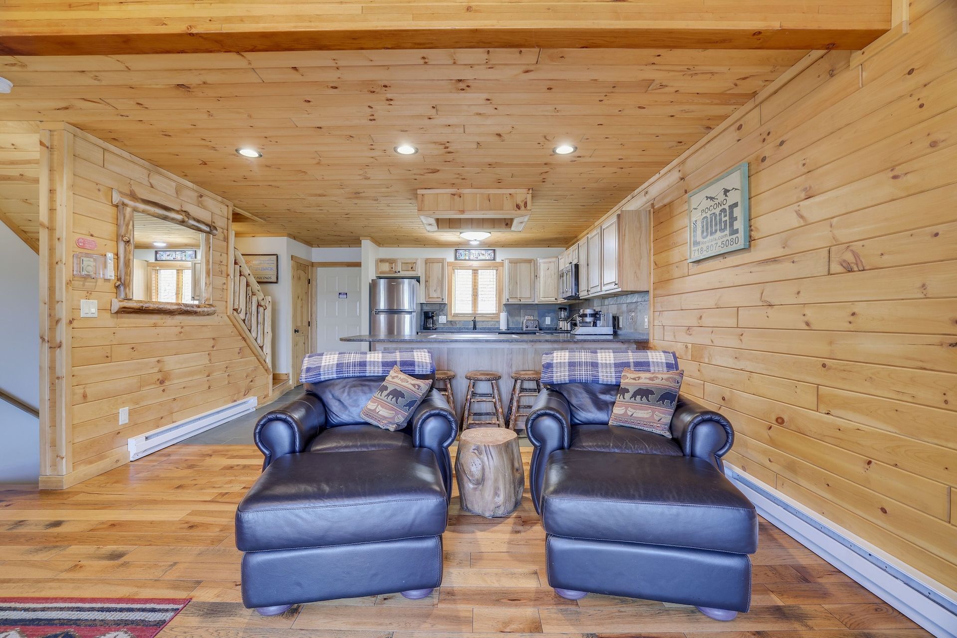 There are two chairs and an ottoman in the living room of a log cabin.