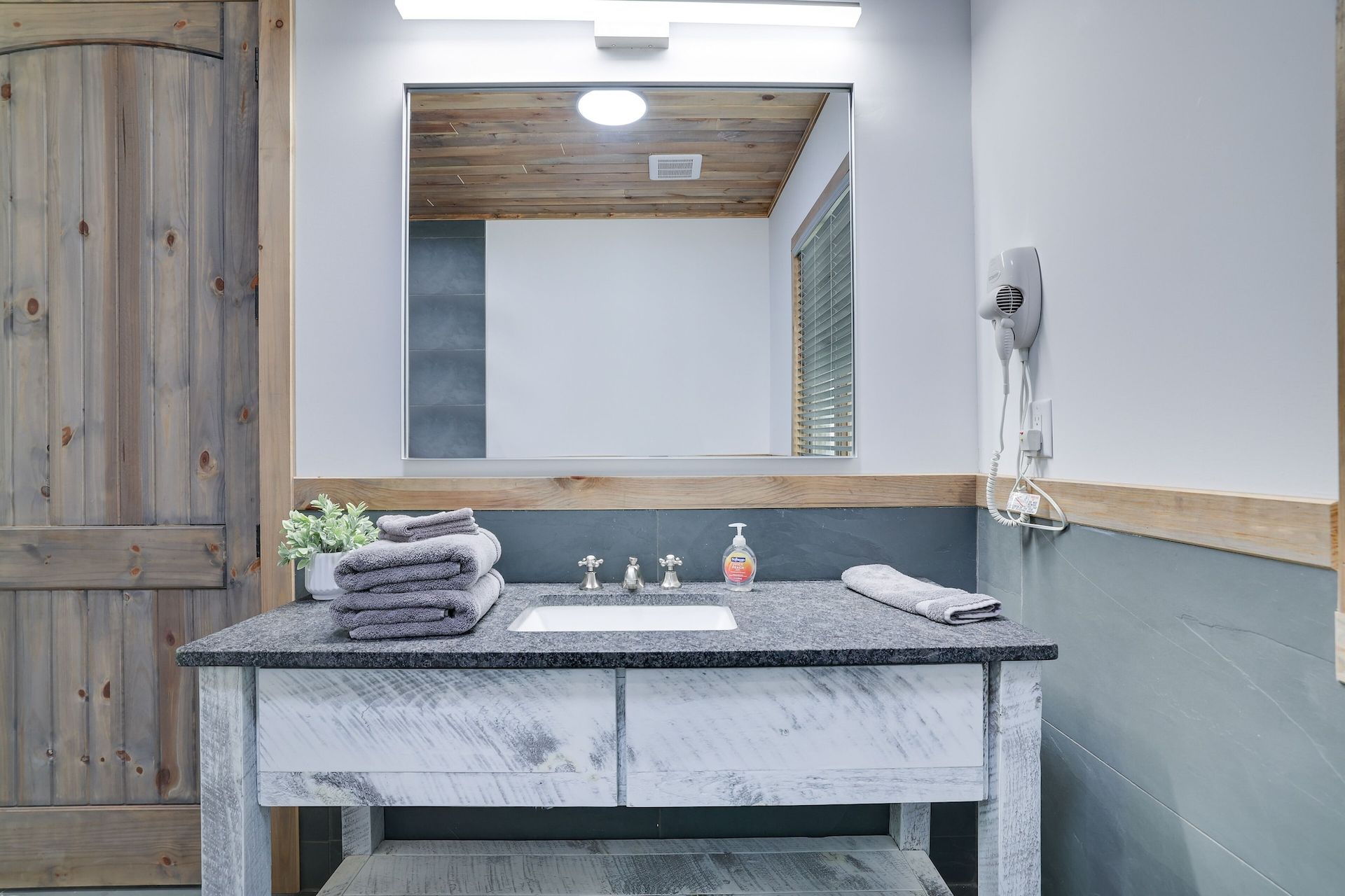 A bathroom with a sink , mirror and towels on the counter.