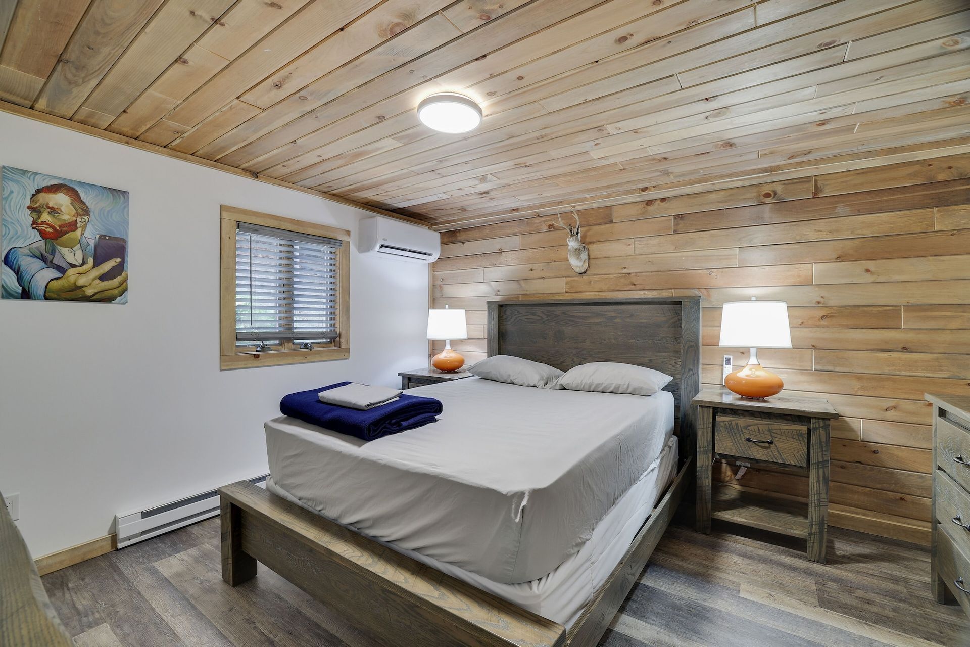 A bedroom with a bed , nightstands , lamps and a painting on the wall.