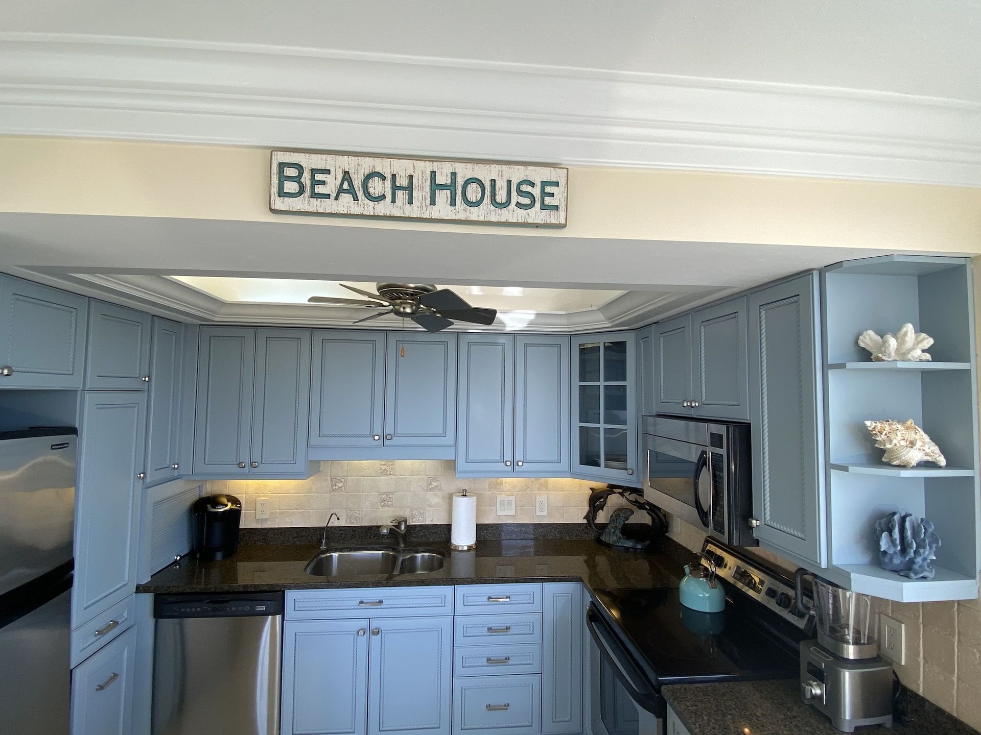 A kitchen with blue cabinets and a sign that says beach house
