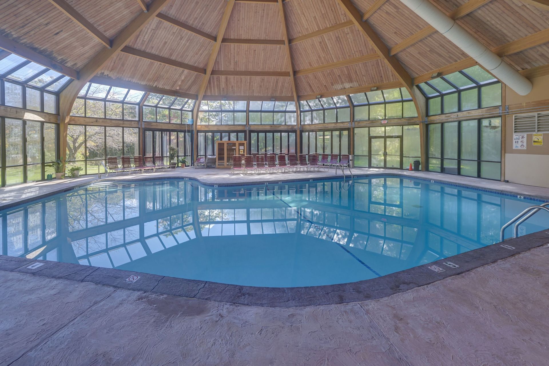 A large indoor swimming pool with a wooden roof and lots of windows.