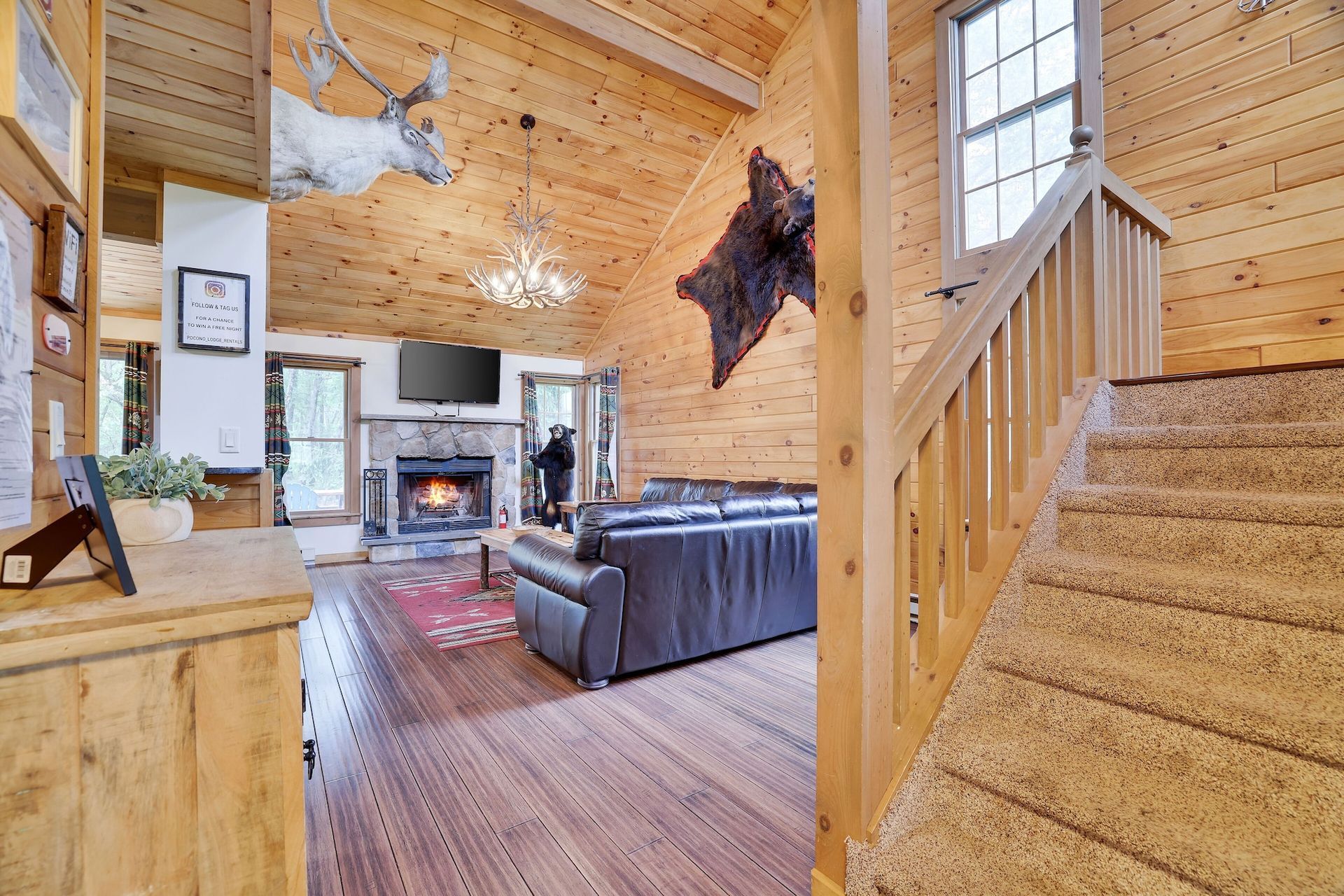 A living room in a log cabin with stairs leading up to the second floor.