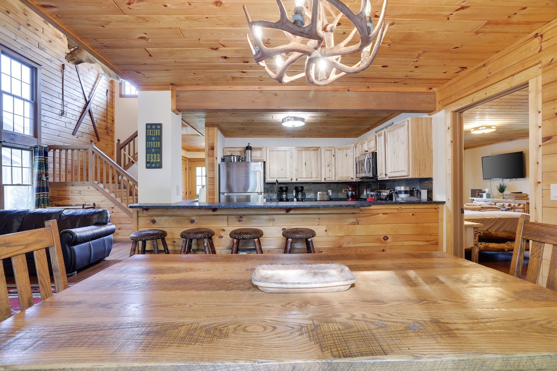 A dining room table in a log cabin with a chandelier hanging from the ceiling.