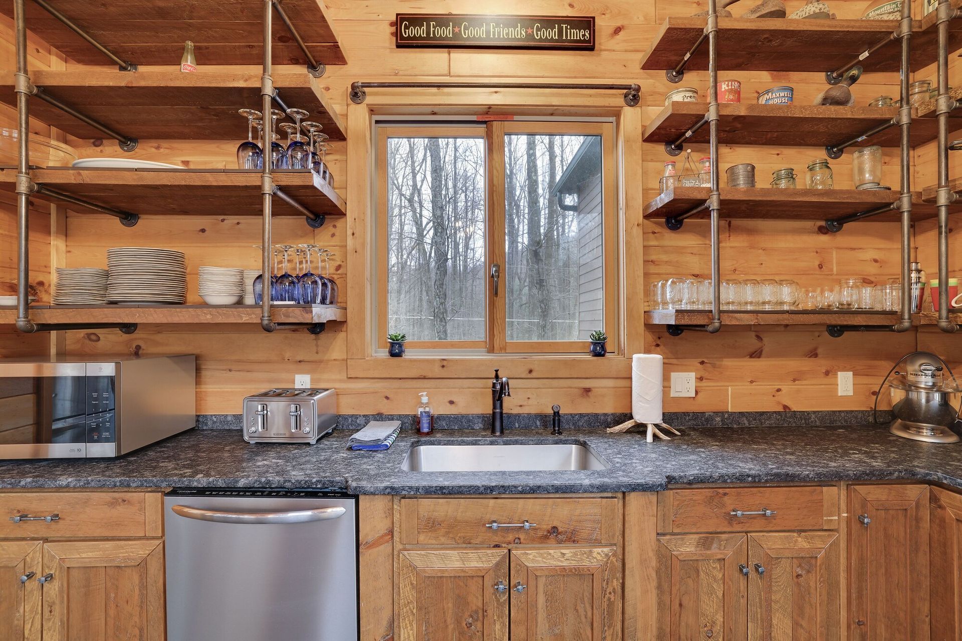 A kitchen with wooden cabinets , stainless steel appliances , a sink , and a window.