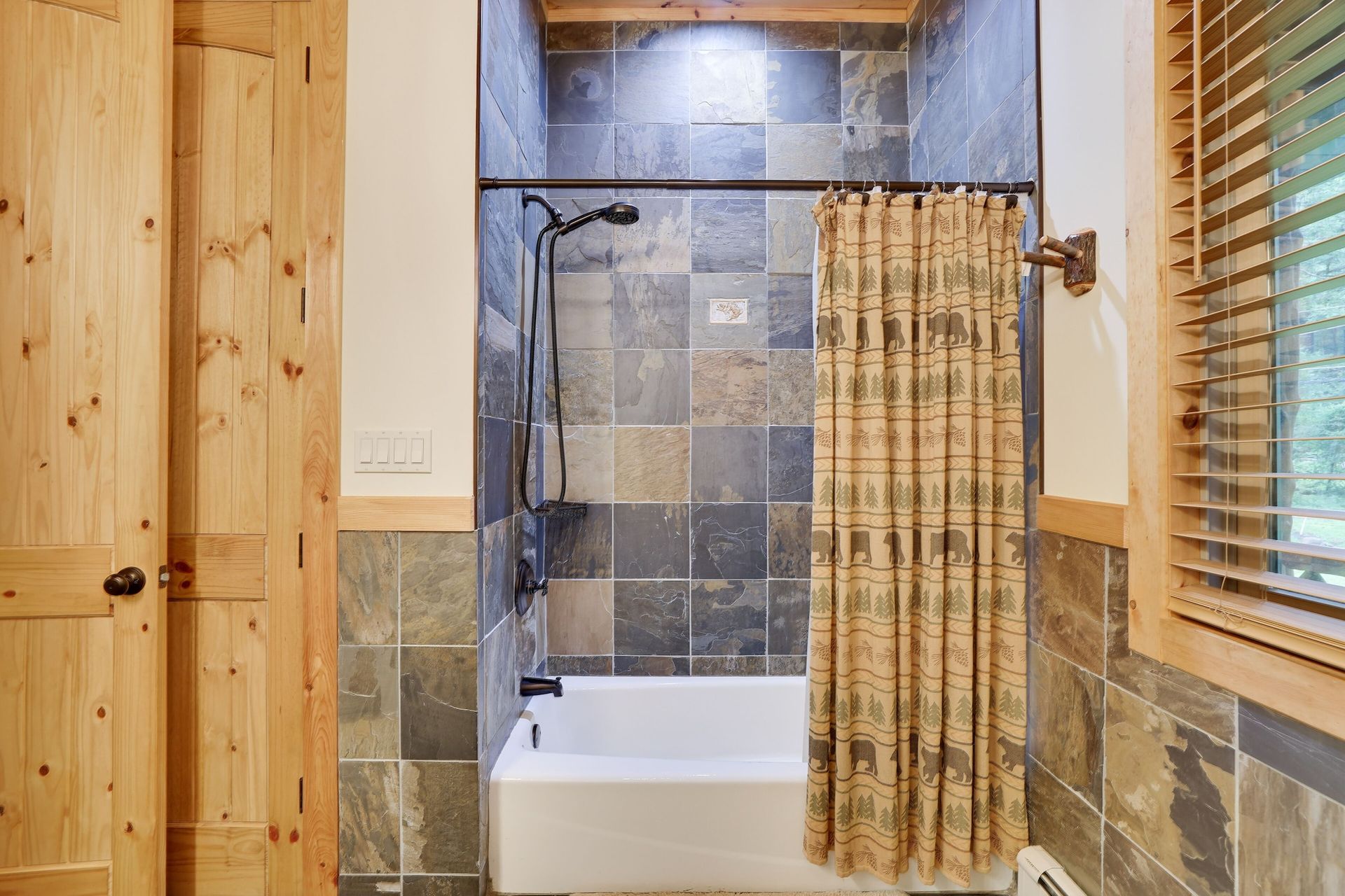 A bathroom with a tub , shower , and window.