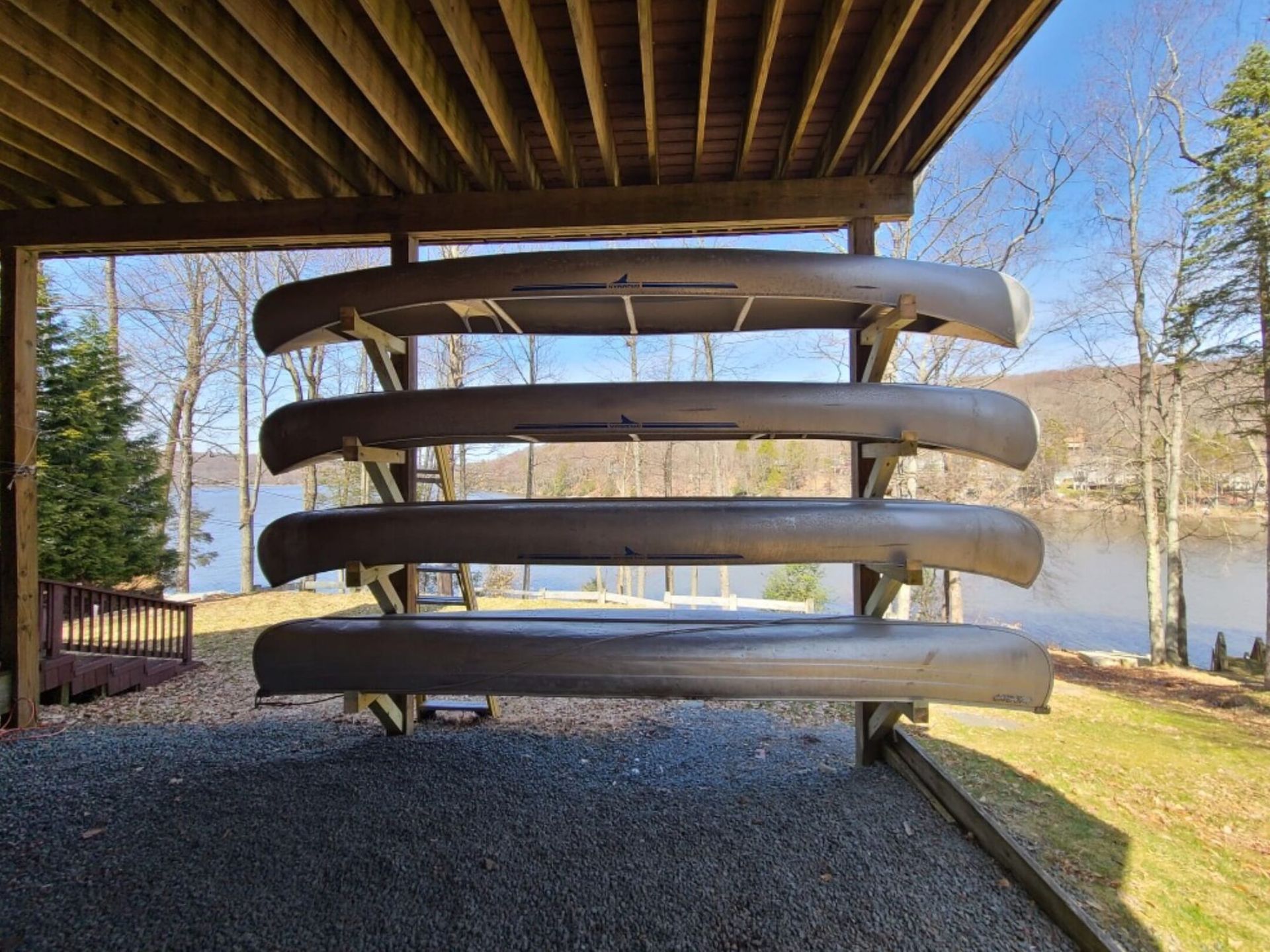 A row of canoes are stacked on top of each other under a roof.