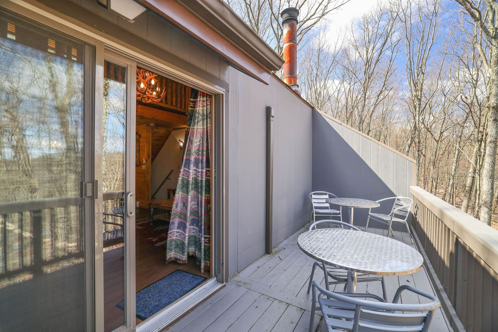 There is a table and chairs on the deck of a house.