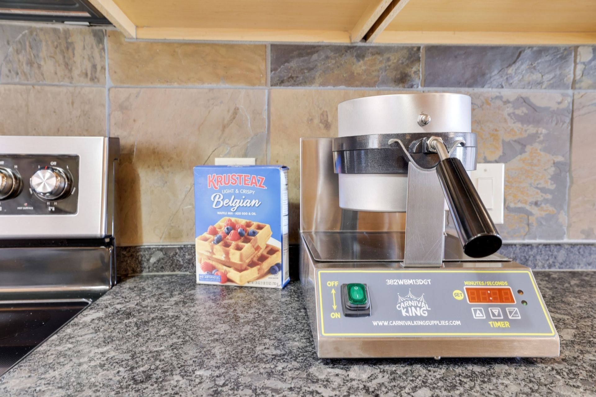 A waffle maker is sitting on a counter next to a box of waffle mix.