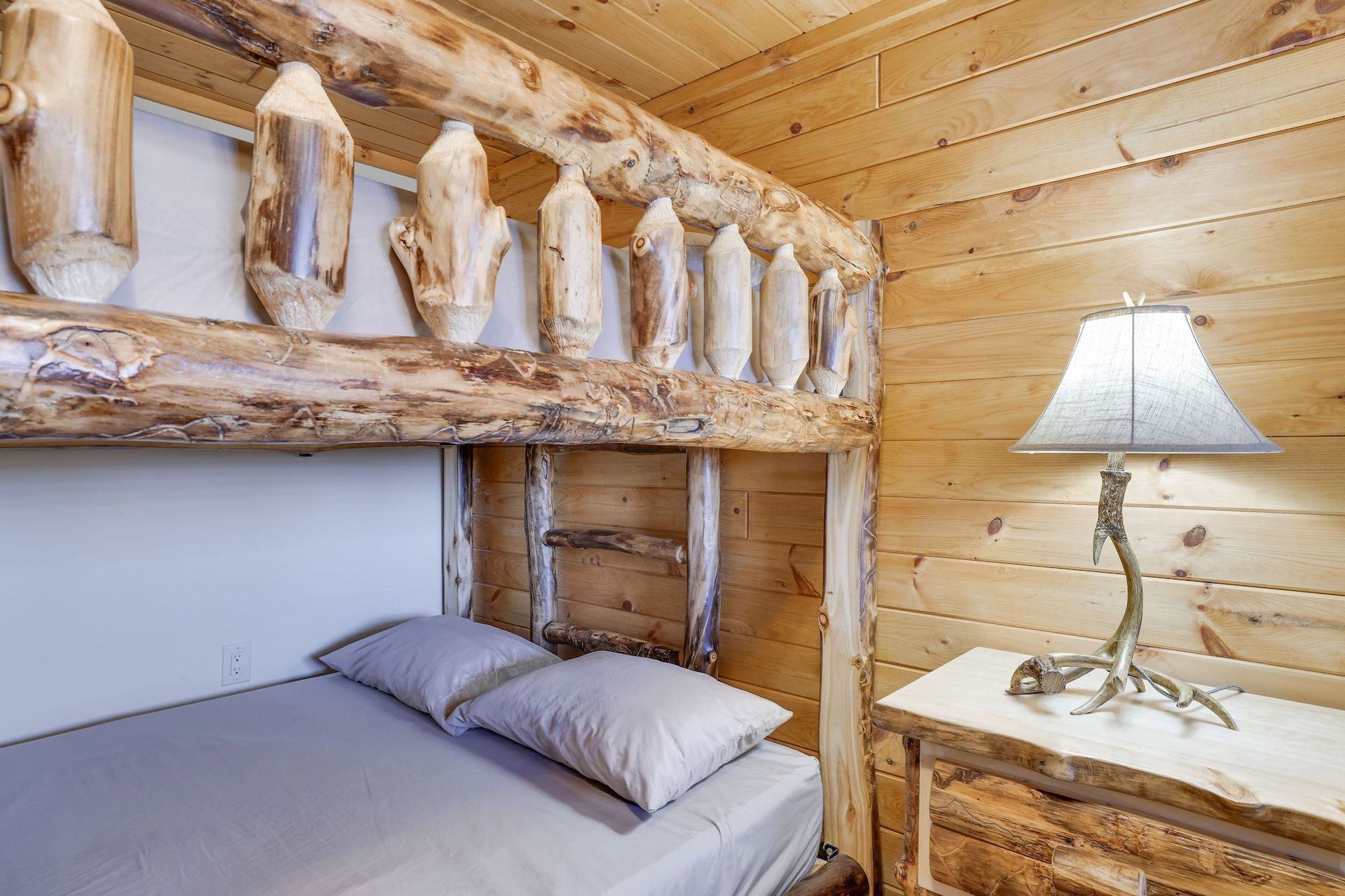 A bedroom in a log cabin with a bunk bed and a lamp.