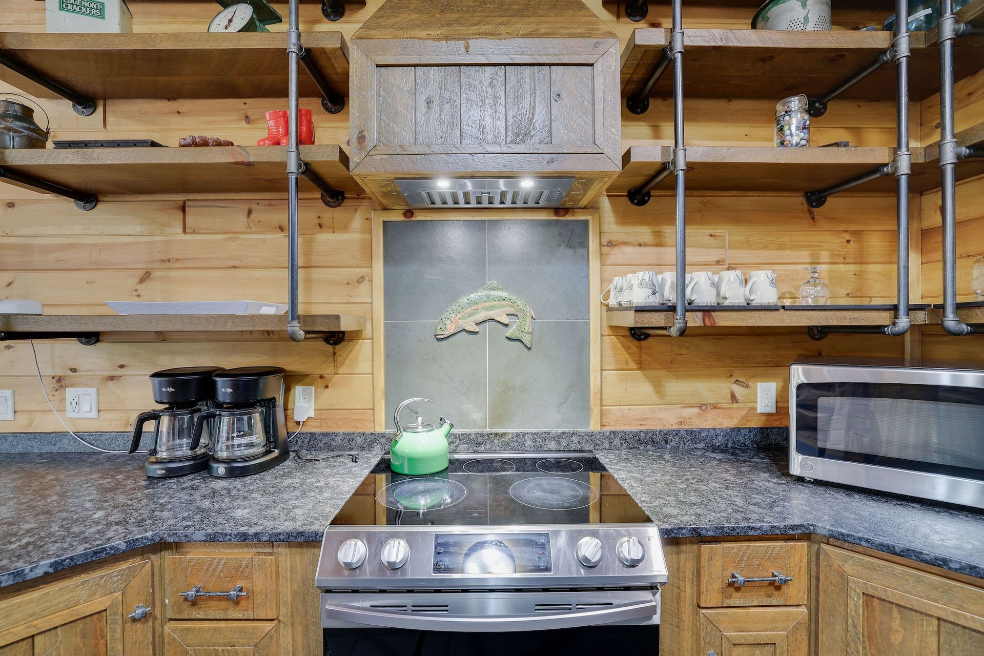 A kitchen with a stove , microwave , coffee maker , and shelves.
