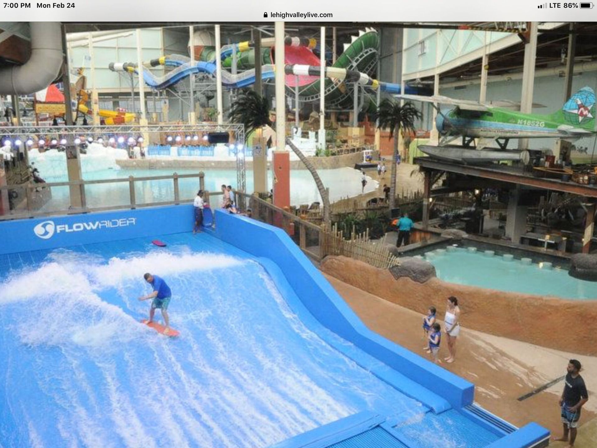 A man is riding a wave on a surfboard in a water park.