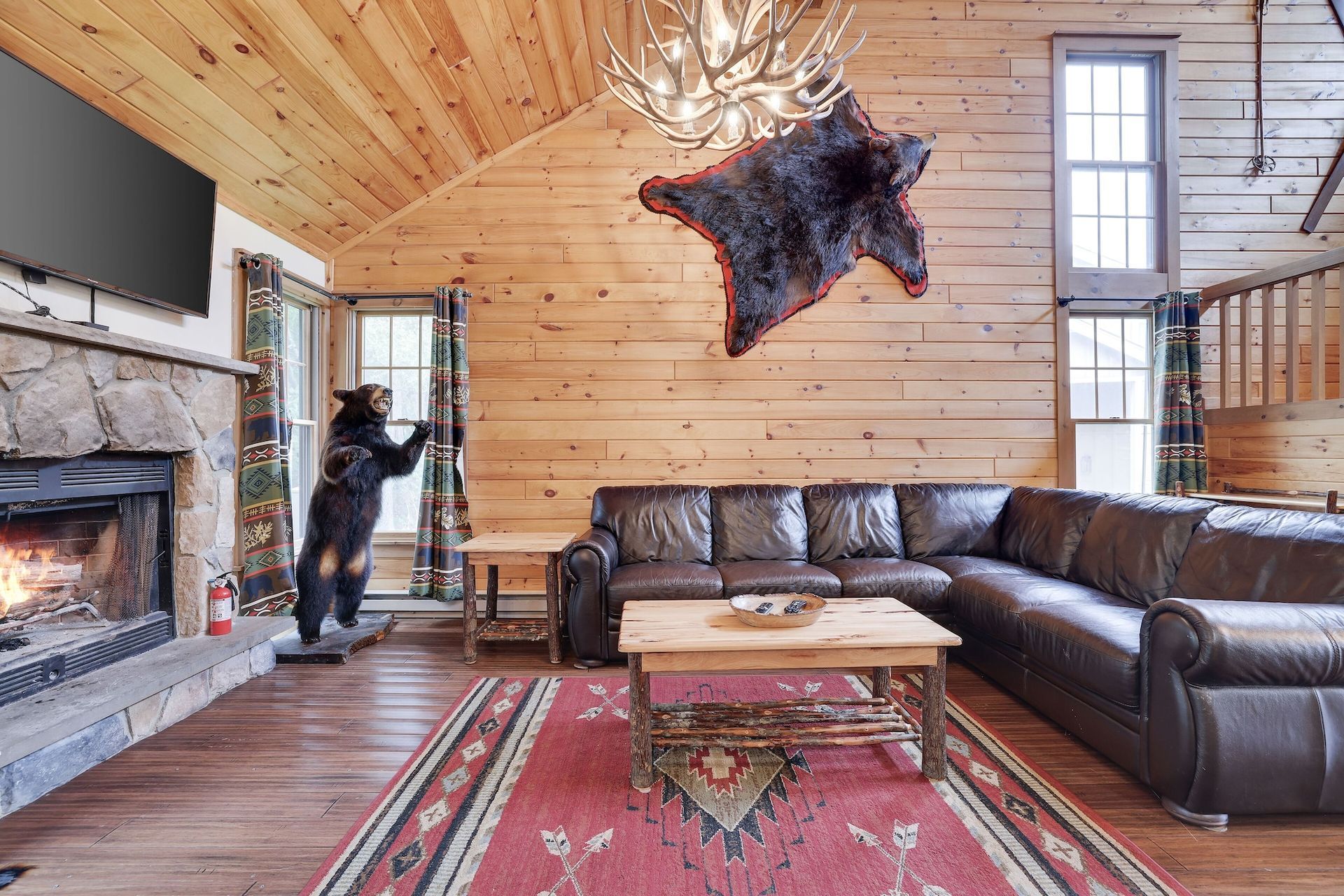 A living room with a couch , fireplace , rug and a bear statue.