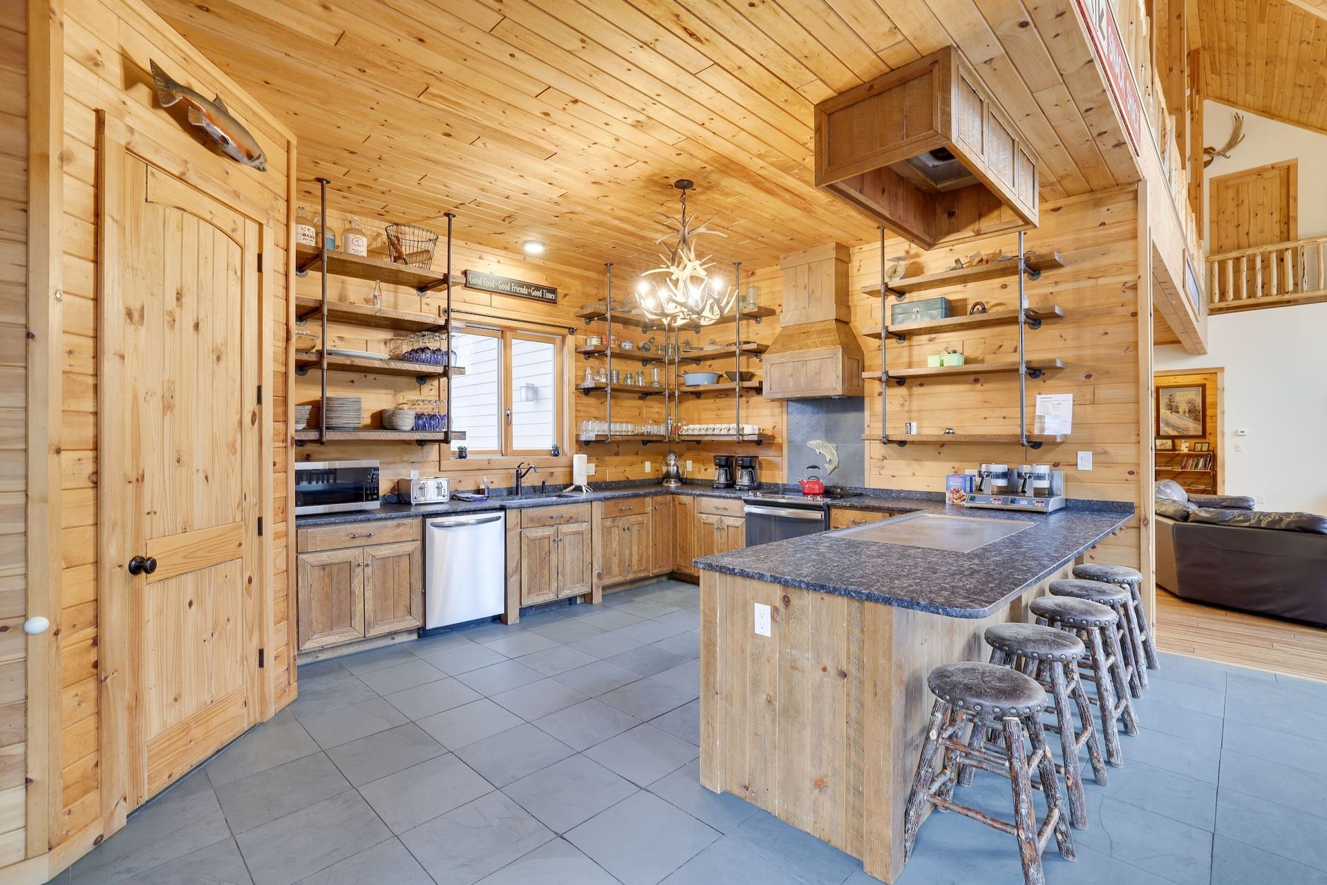 A kitchen in a log cabin with a large island and stools.