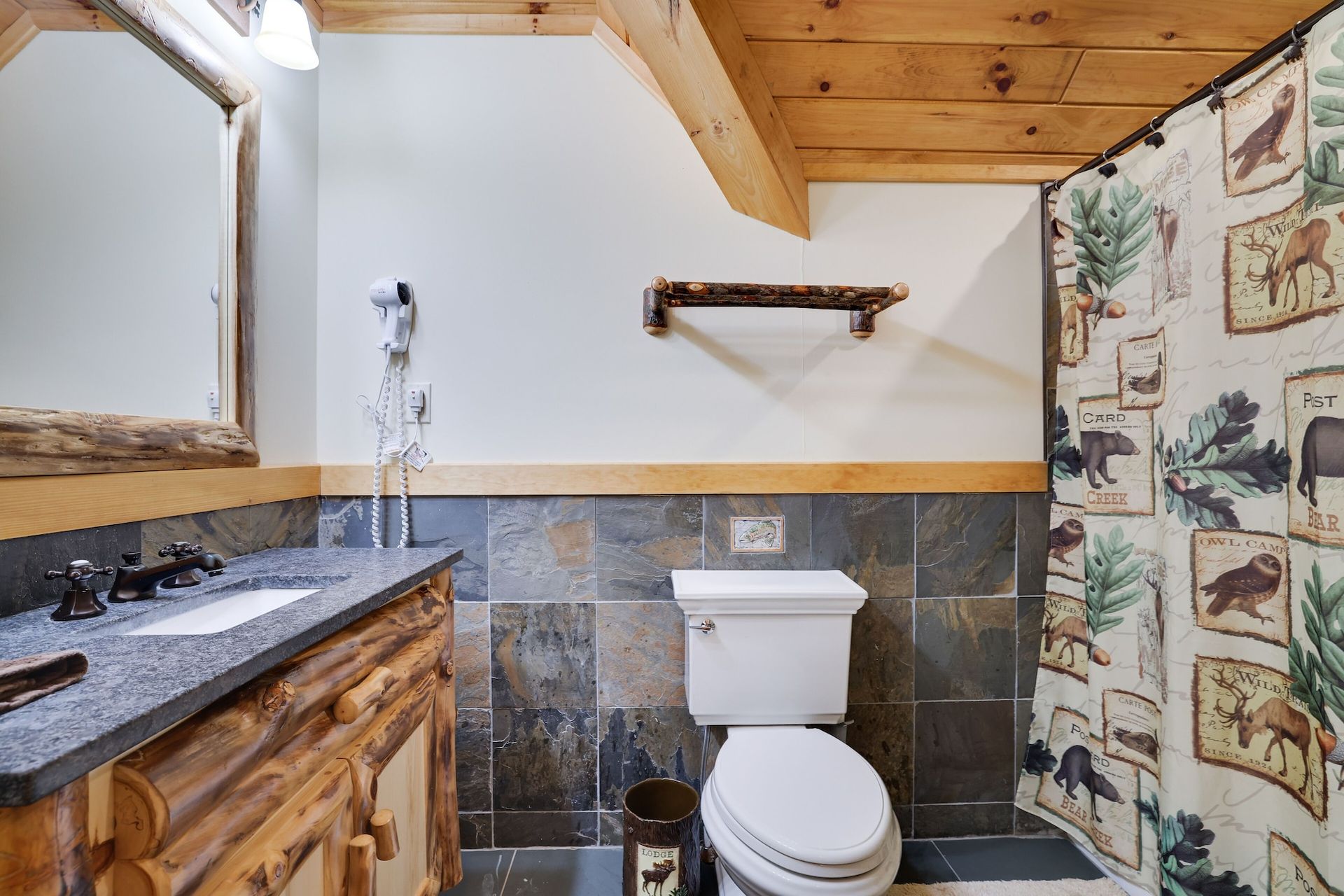 A bathroom with a toilet , sink , mirror and shower curtain.
