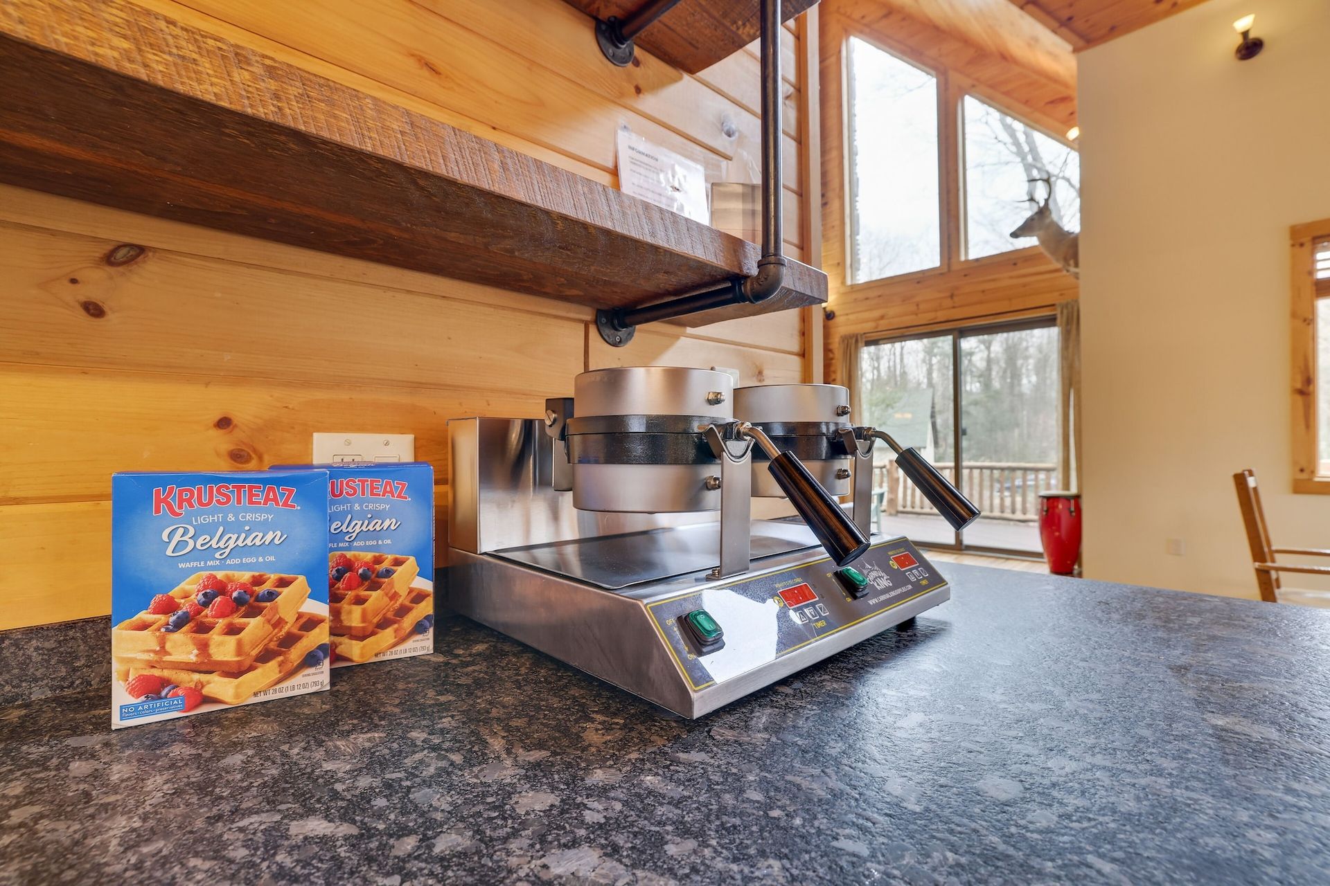 A waffle maker is sitting on a counter next to a box of waffle mix.