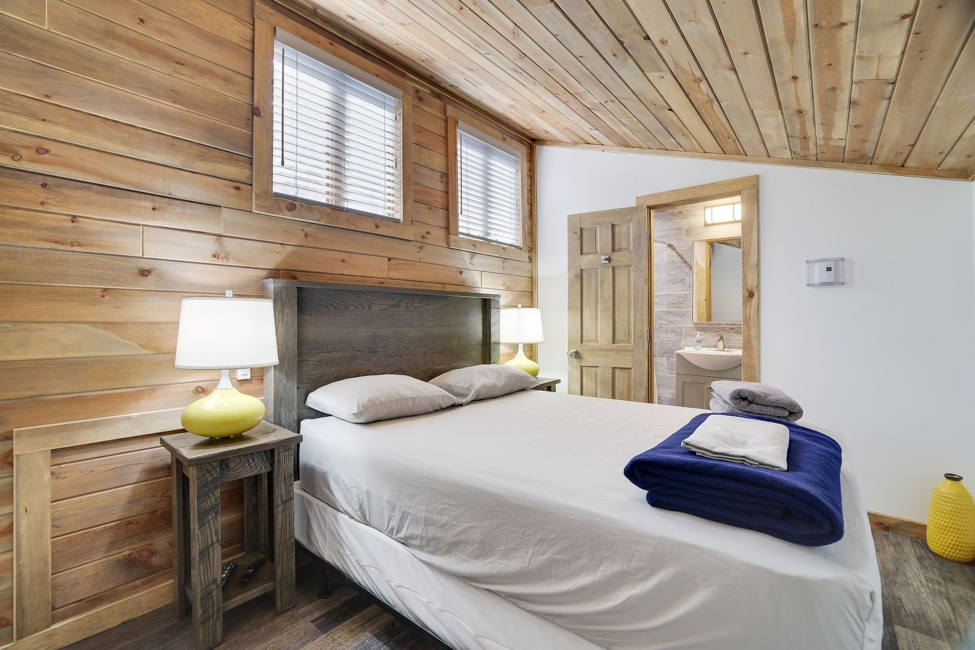 A bedroom with a bed , two lamps , and a bathroom.