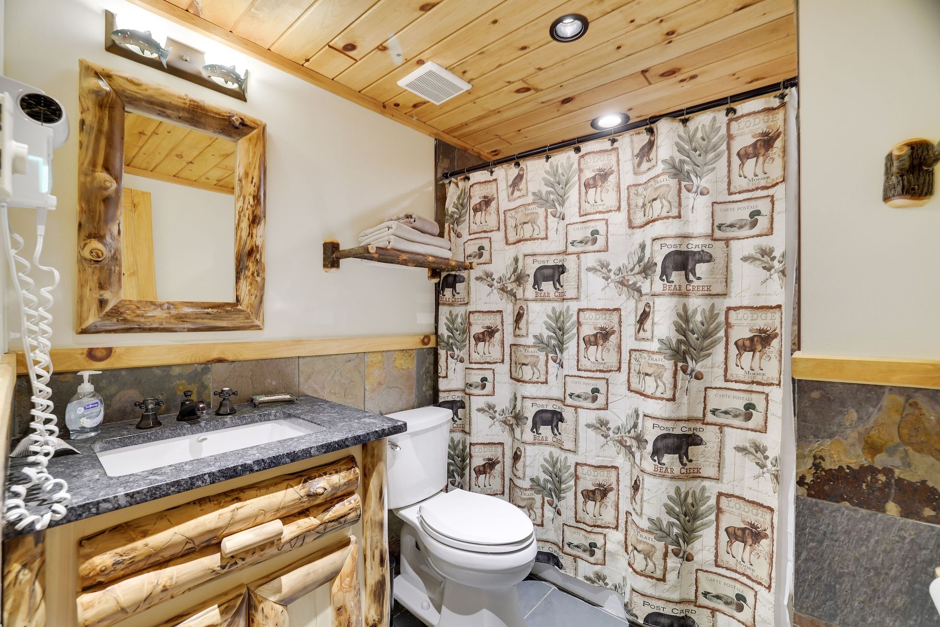 A bathroom with a toilet , sink , mirror and shower curtain.