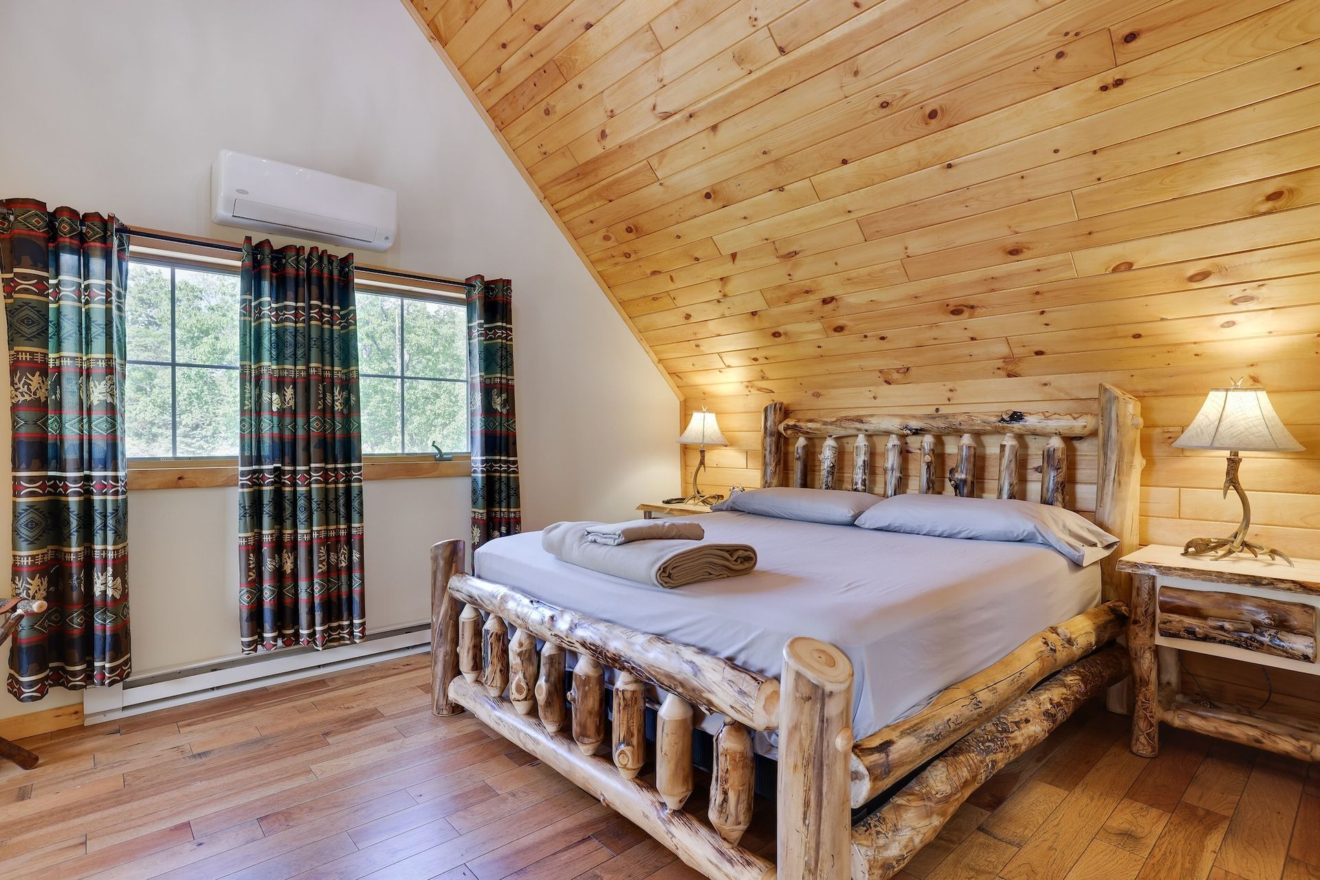 A bedroom in a log cabin with a king size log bed.