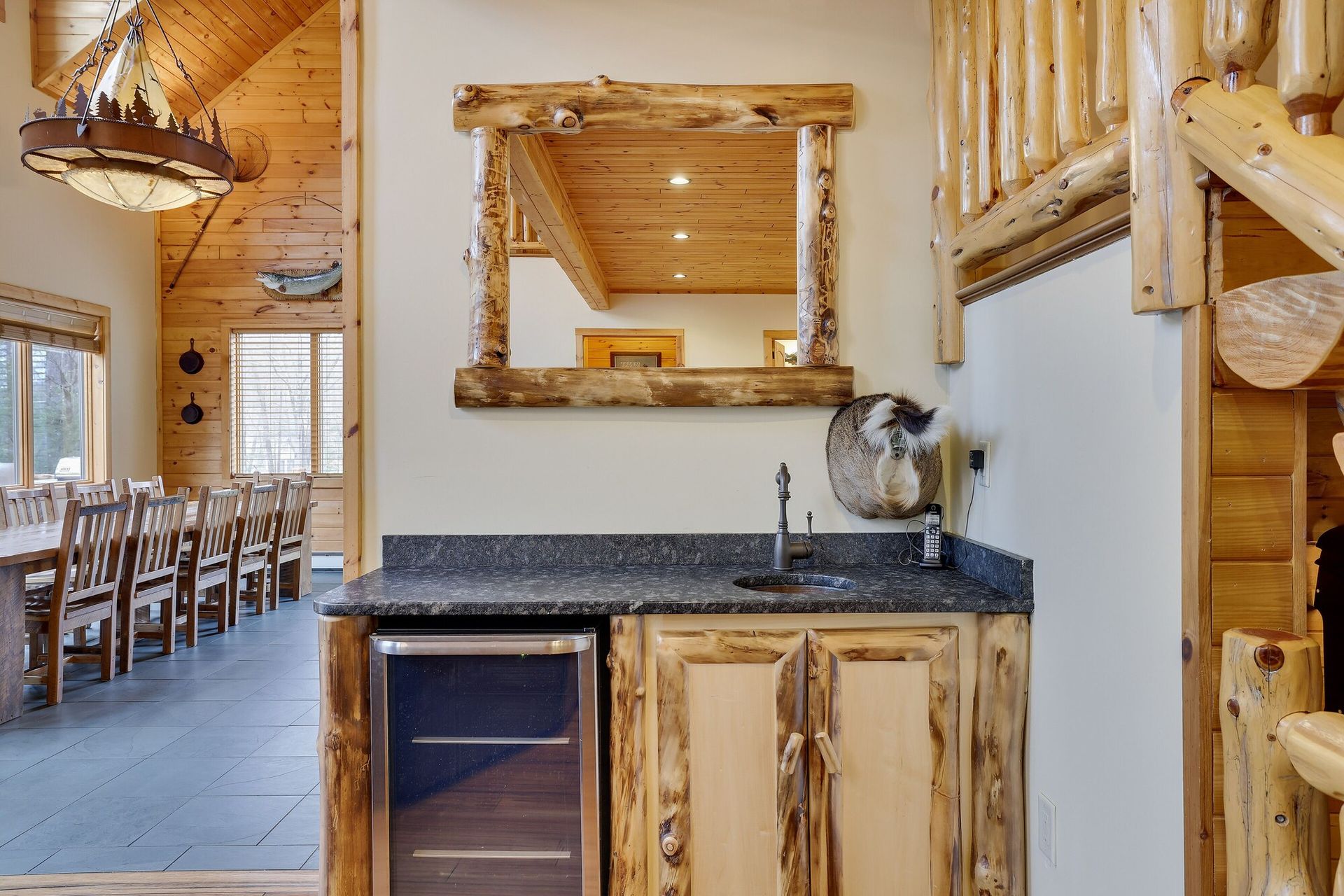 A kitchen in a log cabin with a sink and a refrigerator.