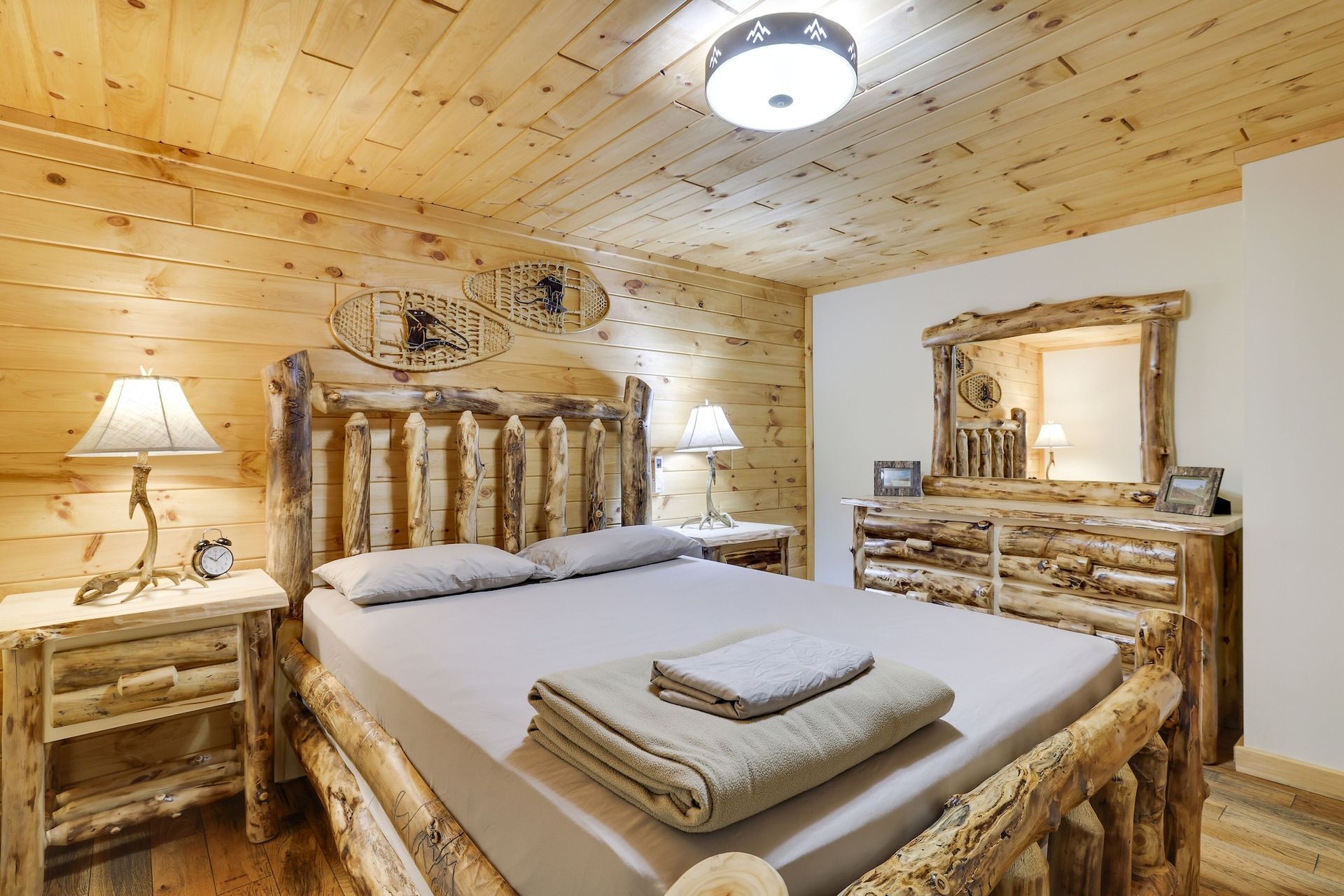 A bedroom with a log bed , dresser , nightstand and mirror.