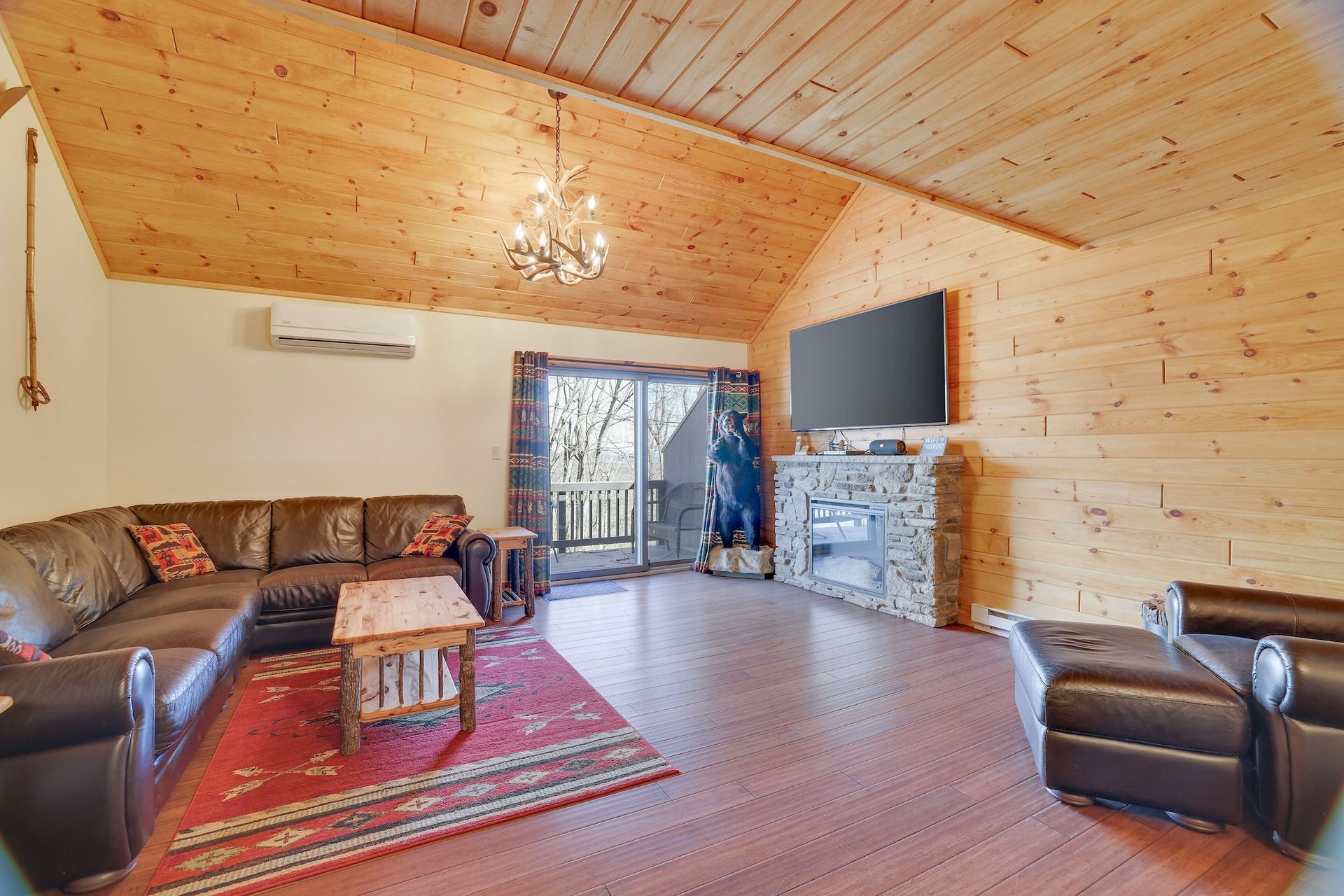 A living room with a couch , chairs , and a flat screen tv.