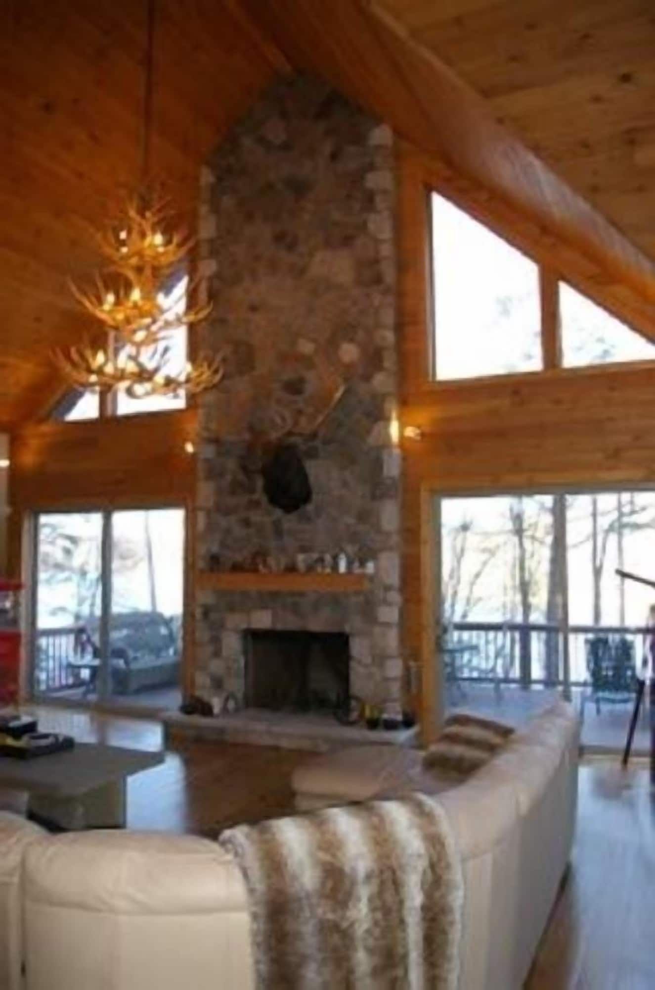 A living room with a large stone fireplace and lots of windows