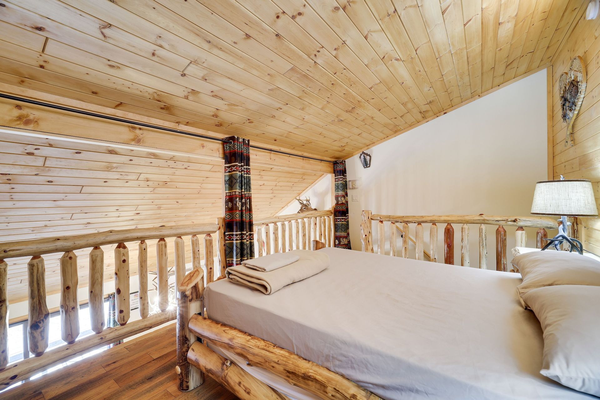 There is a bed in the middle of the room with a wooden ceiling.