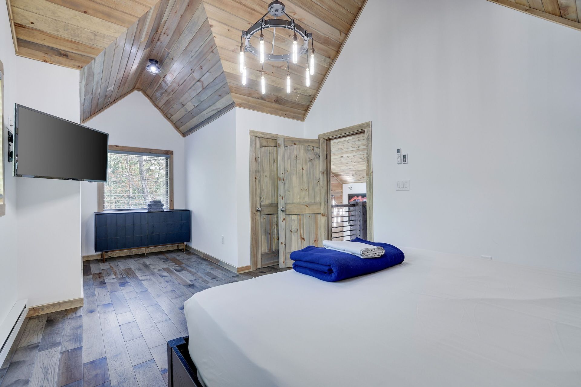 A bedroom with a bed , television , and wooden floors.
