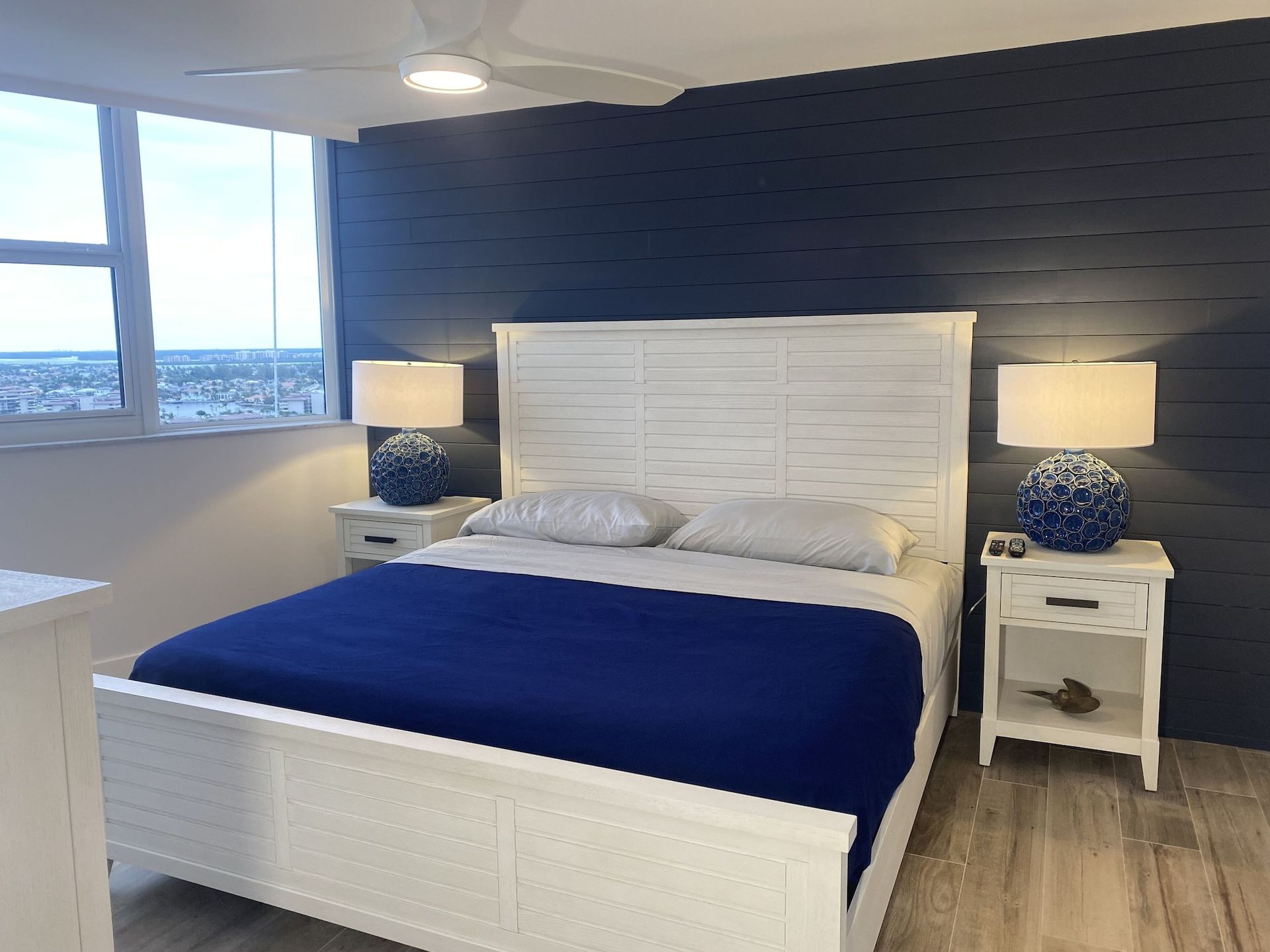 A bedroom with a bed , nightstands , lamps and a ceiling fan.