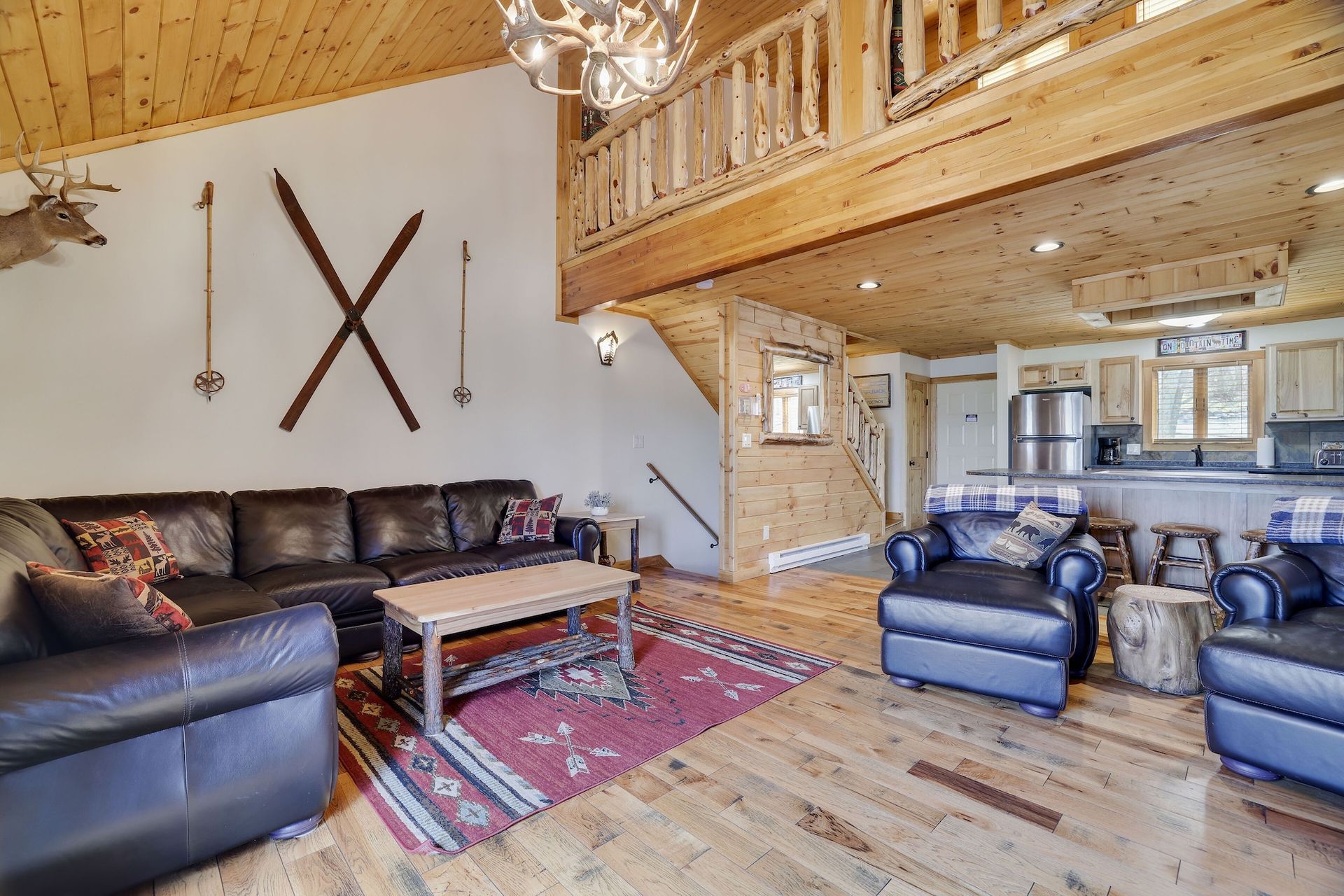 A living room with a couch , chairs , coffee table and skis on the wall.