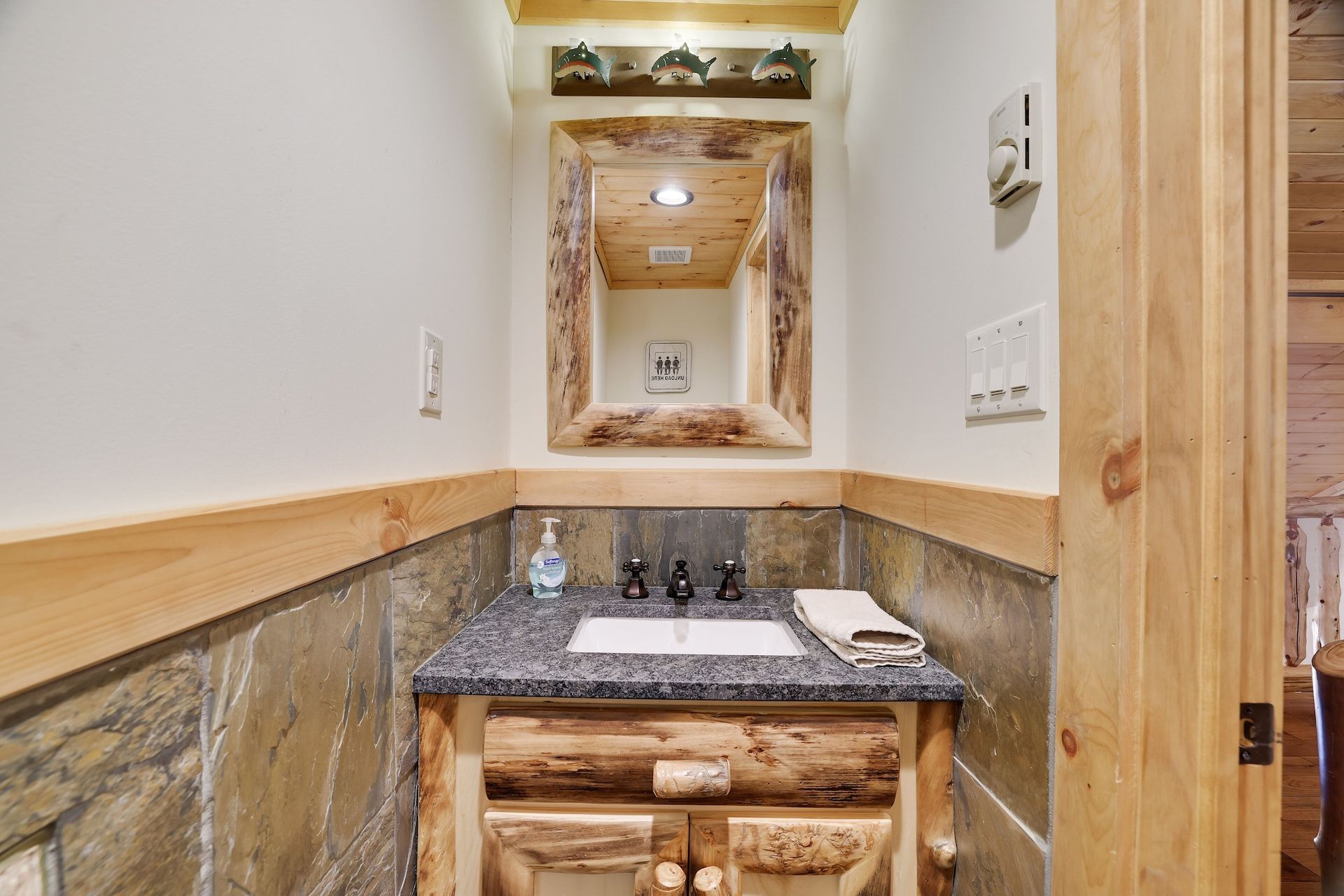 A bathroom with a sink , mirror and wooden cabinets.