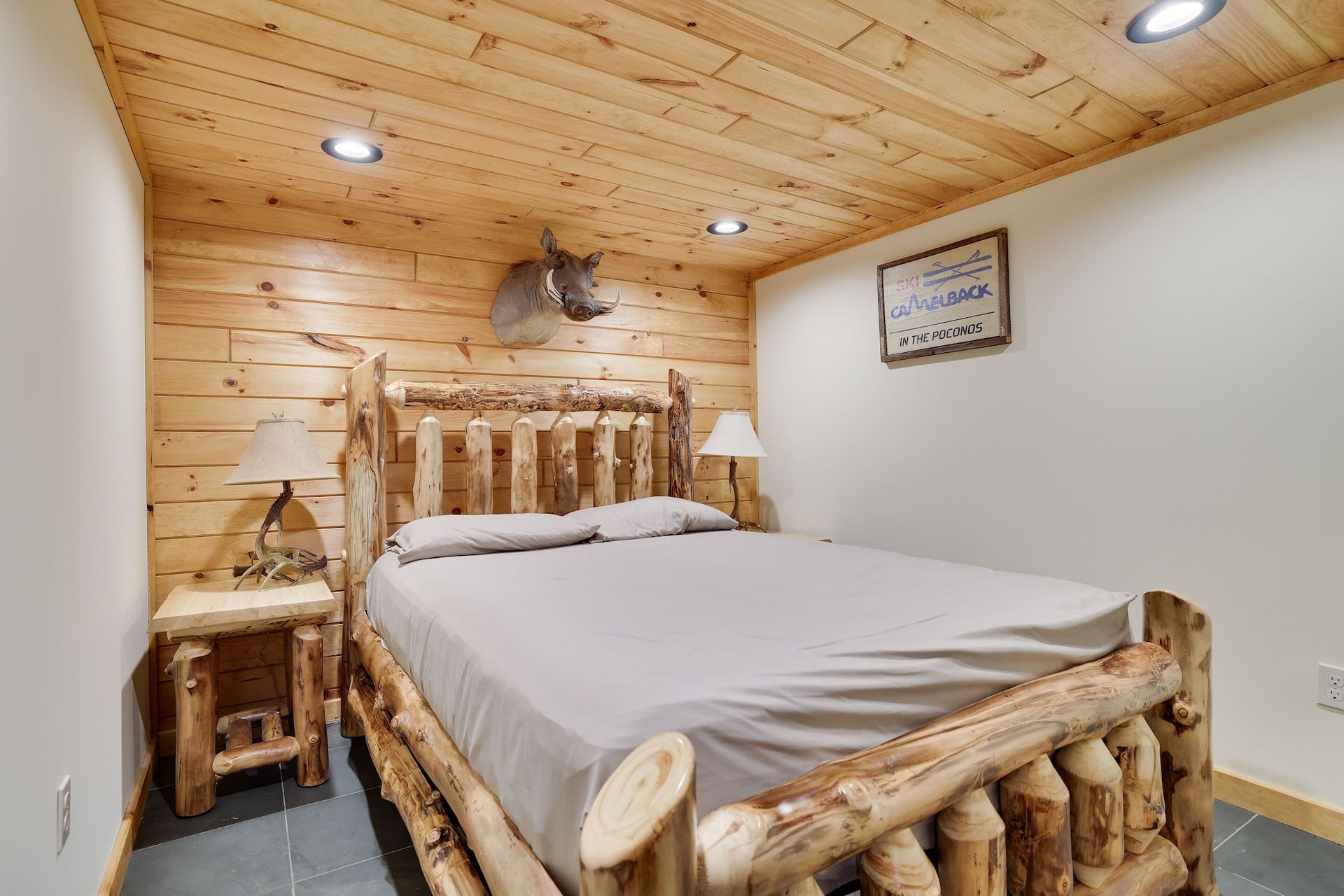 A bedroom with a log bed and a deer head on the wall.