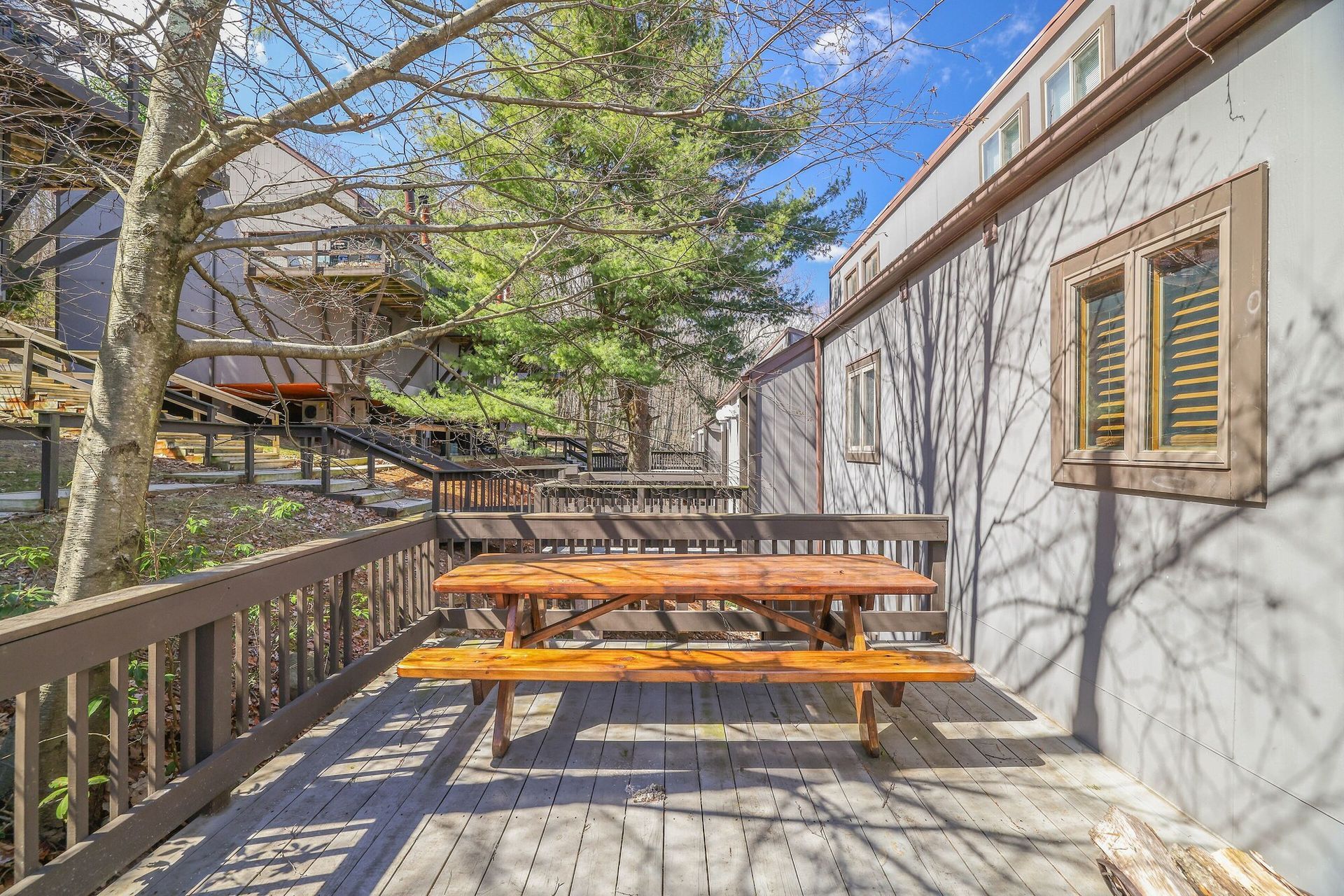 A wooden picnic table is sitting on a patio next to a building.