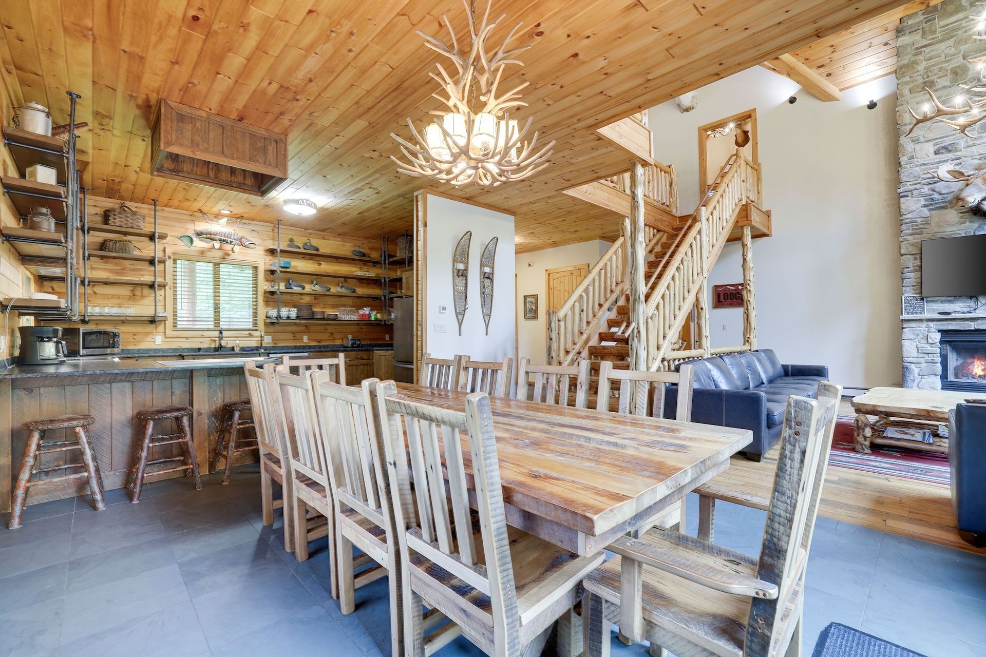 A dining room table and chairs in a log cabin with a chandelier hanging from the ceiling.