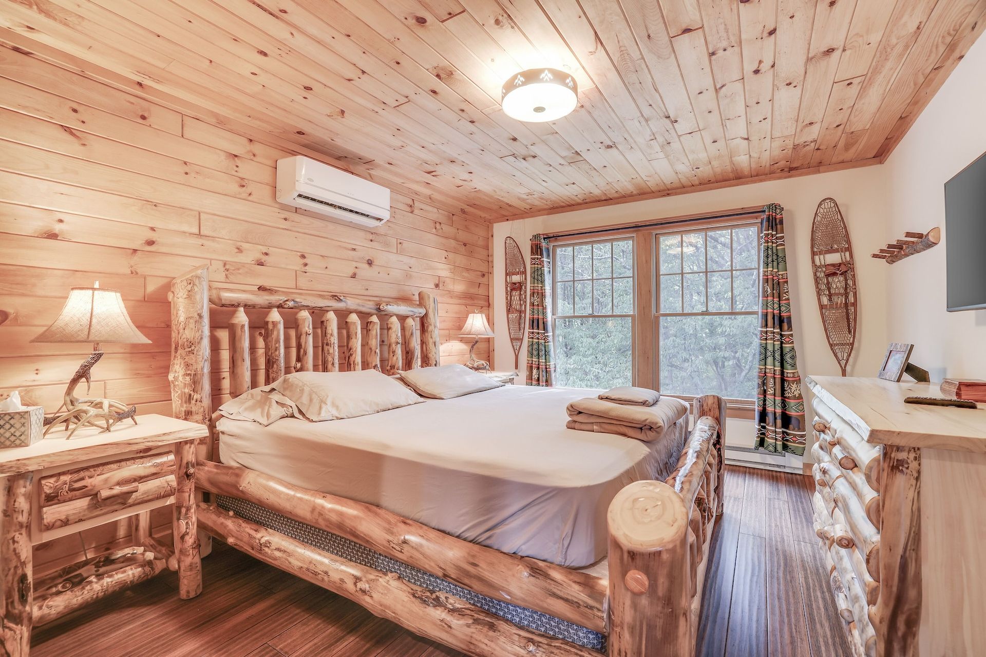 A bedroom in a log cabin with a king size bed and a television.