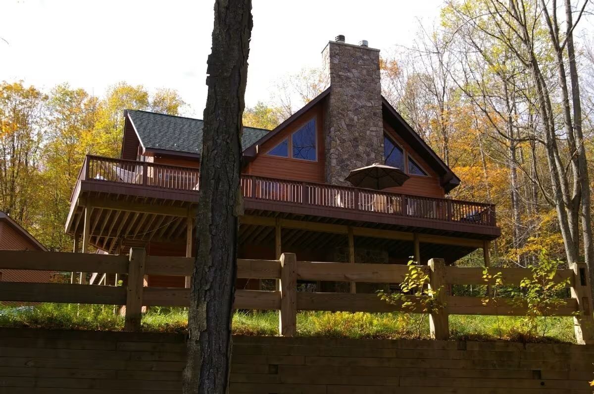 A large house with a fence around it is surrounded by trees