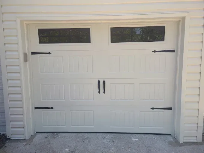 White garage door with black hardware and rectangular windows.