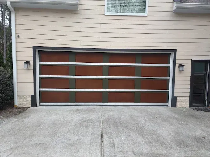 Modern brown garage door with aluminum accents on a concrete driveway.