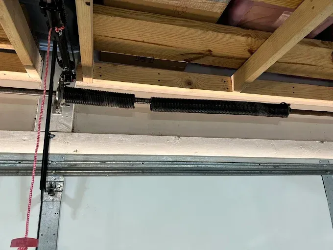 Garage door spring mechanism with visible springs and supporting beams.