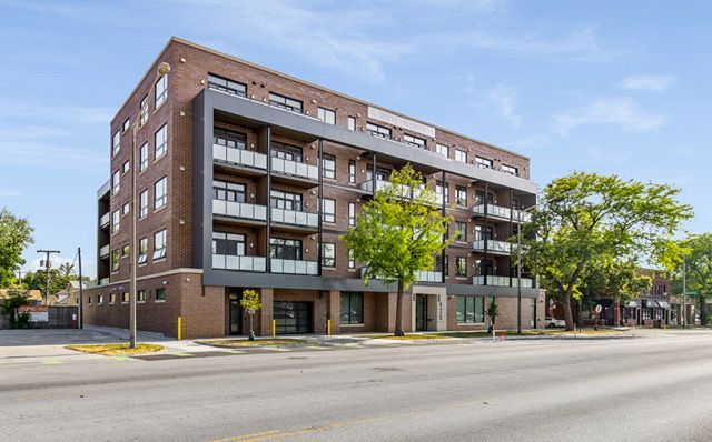 Multi-story brick building with balconies, street view.