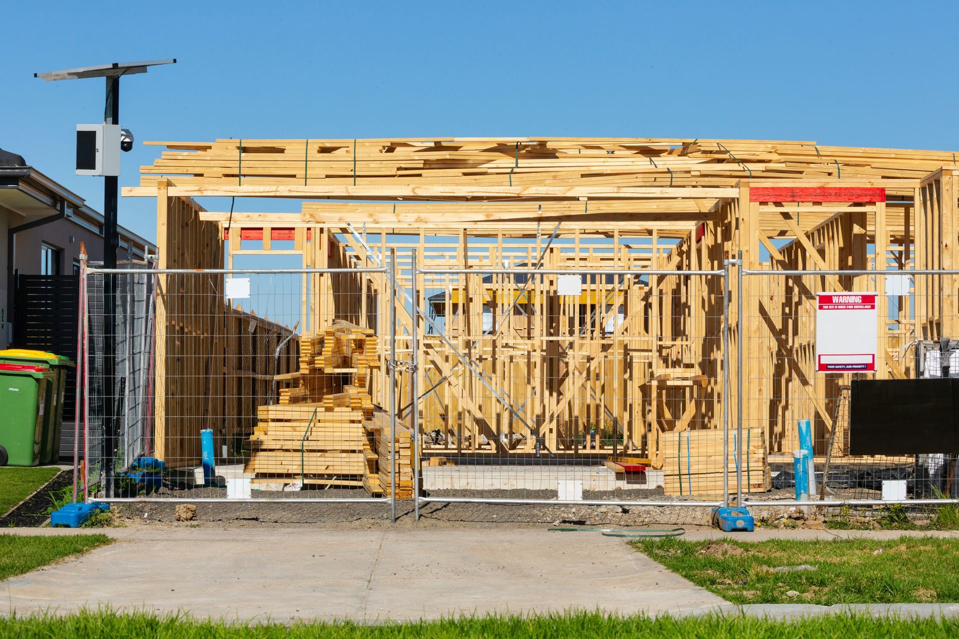 House under construction with wooden framing, exposed walls, and tools in the front yard