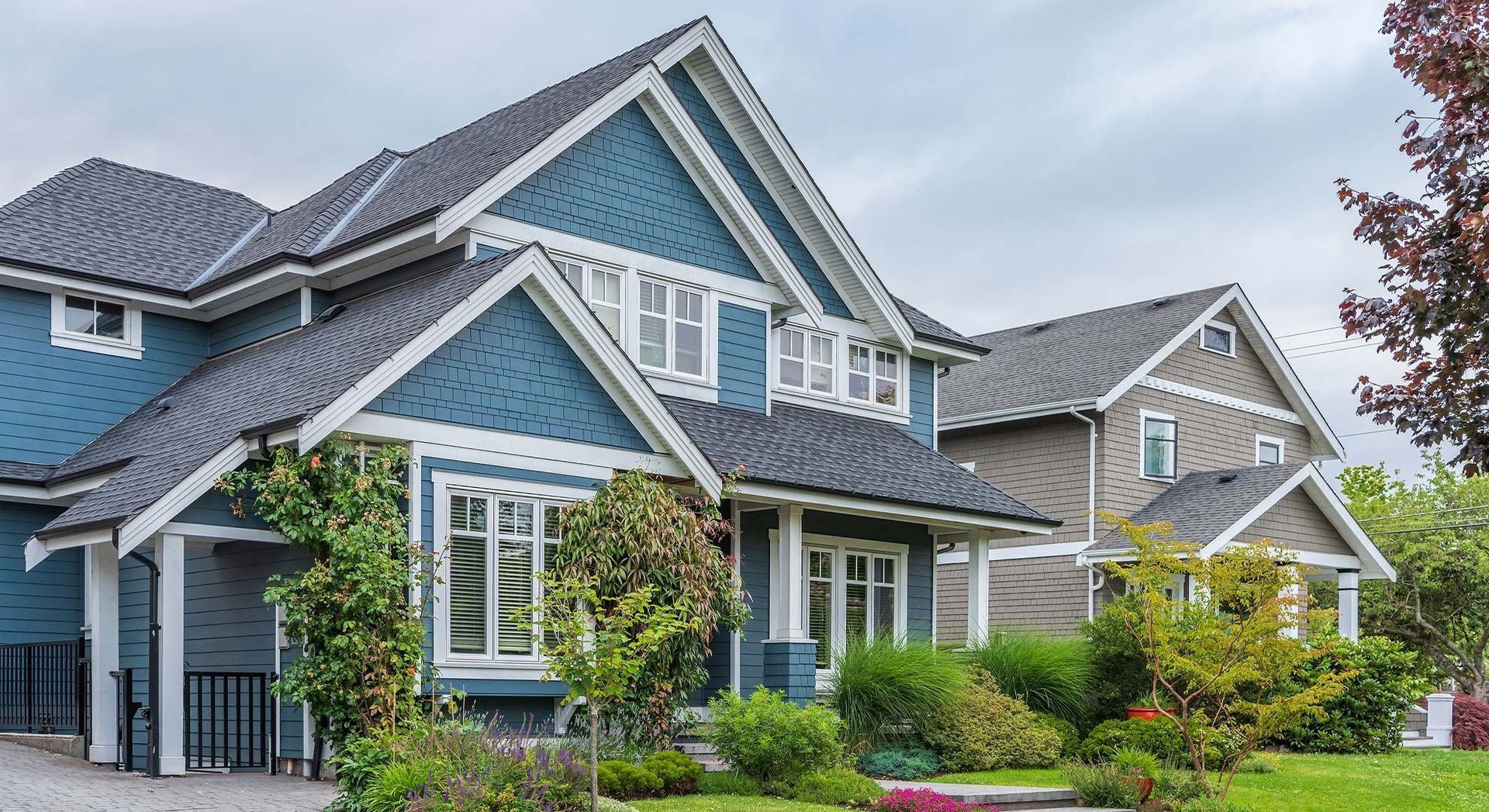 A blue and white house with a gray roof is sitting on top of a lush green lawn.