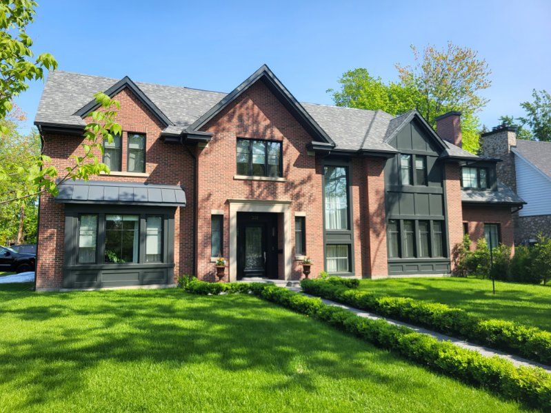 Une grande maison en brique avec une pelouse verte luxuriante devant elle.