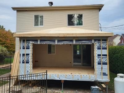 Une maison est en cours de rénovation avec un porche et une clôture.