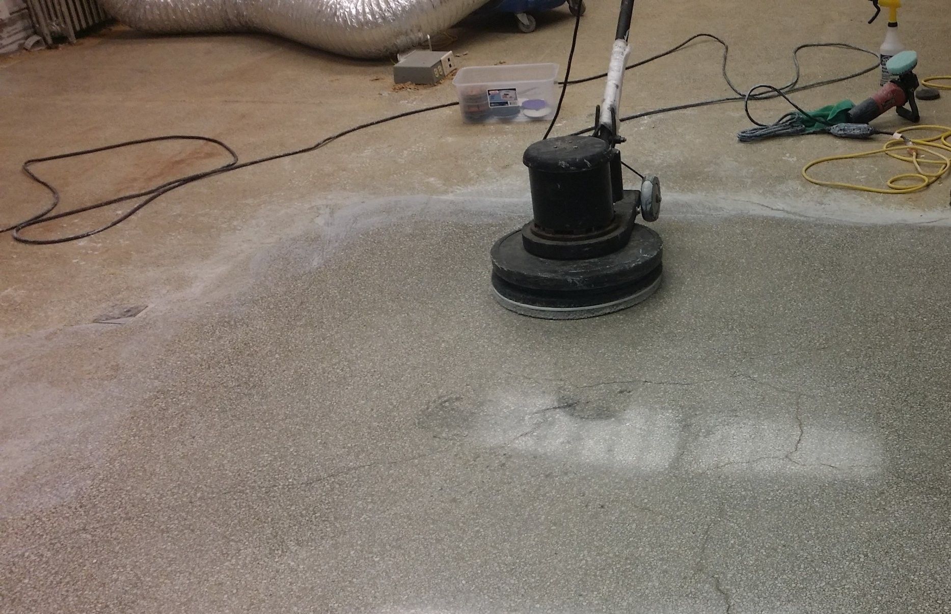 Floor buffer cleaning a carpeted floor with wet cleaning solution visible around it