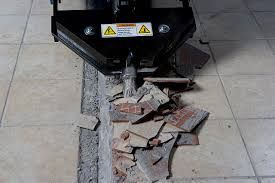 Black dumpster tipping broken bricks and debris onto a sidewalk, with warning labels visible